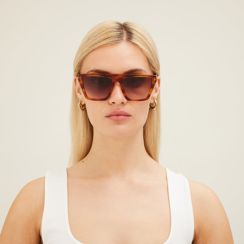 Woman wearing brown sunglasses against a plain background