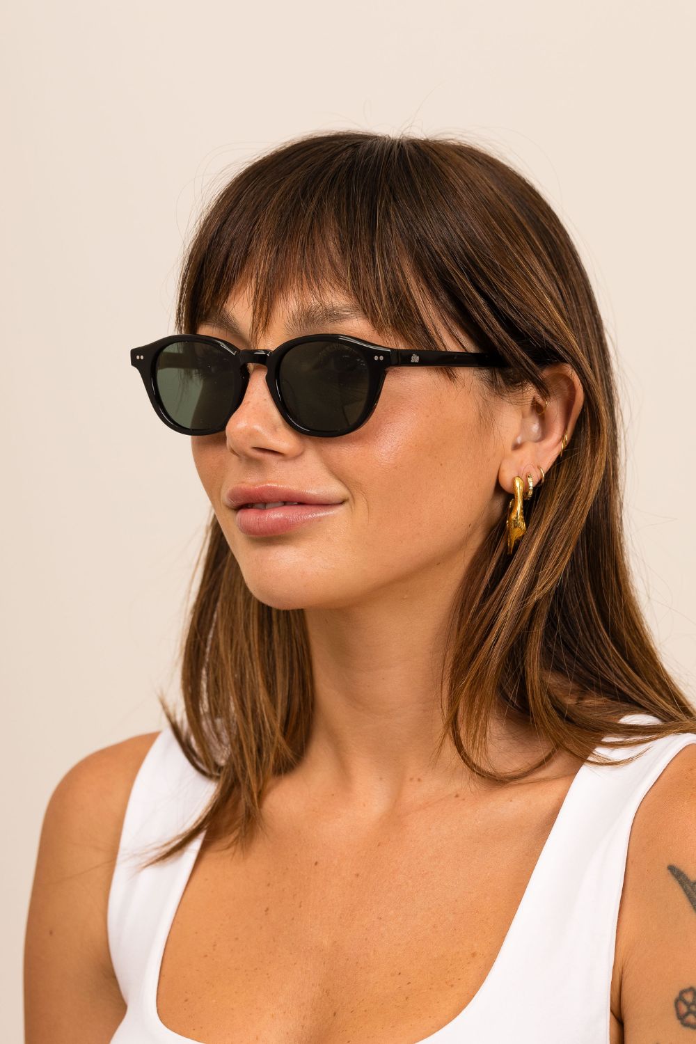 Woman wearing black sunglasses with a neutral background