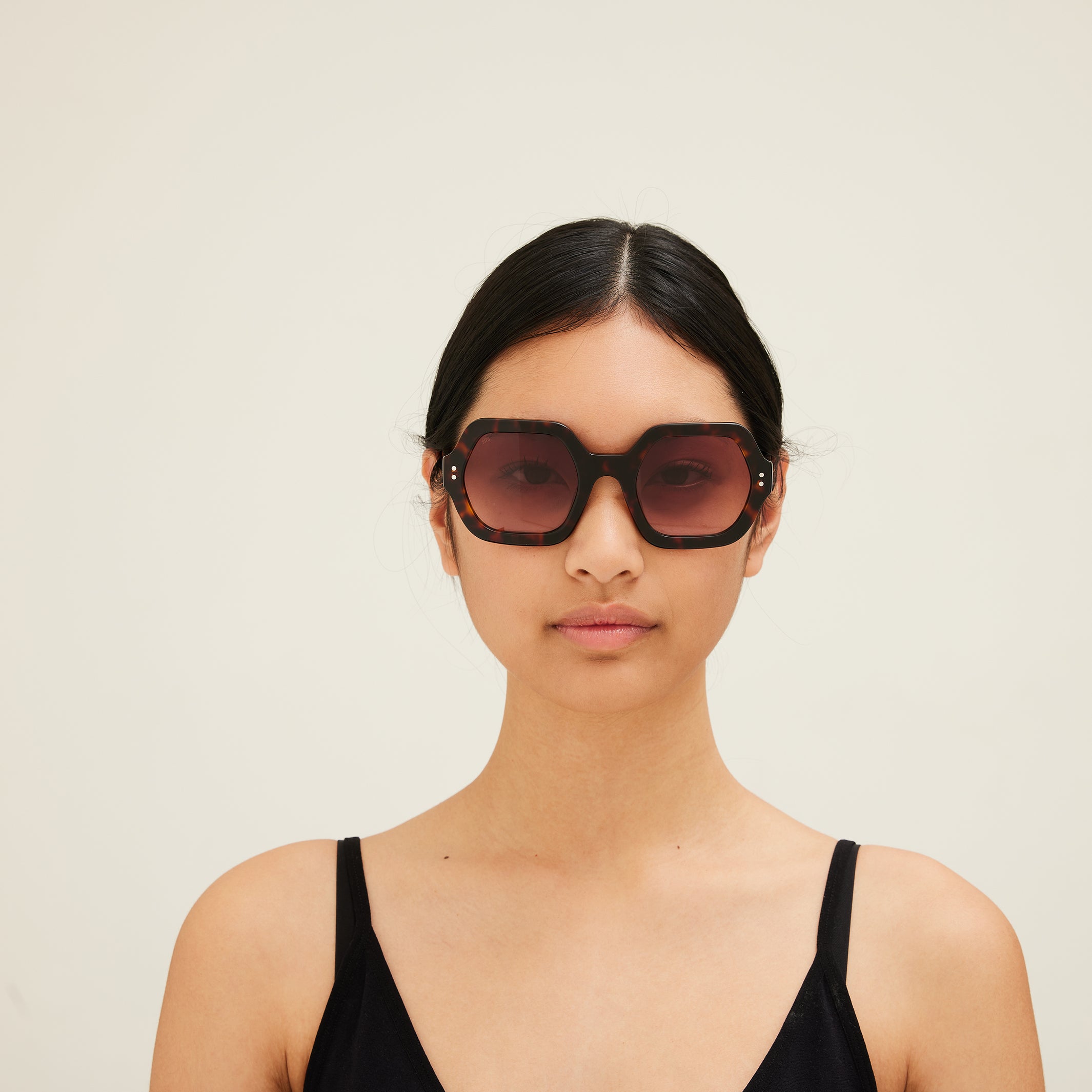 Woman wearing sunglasses with tortoiseshell frame and gradient lenses on a white background. 