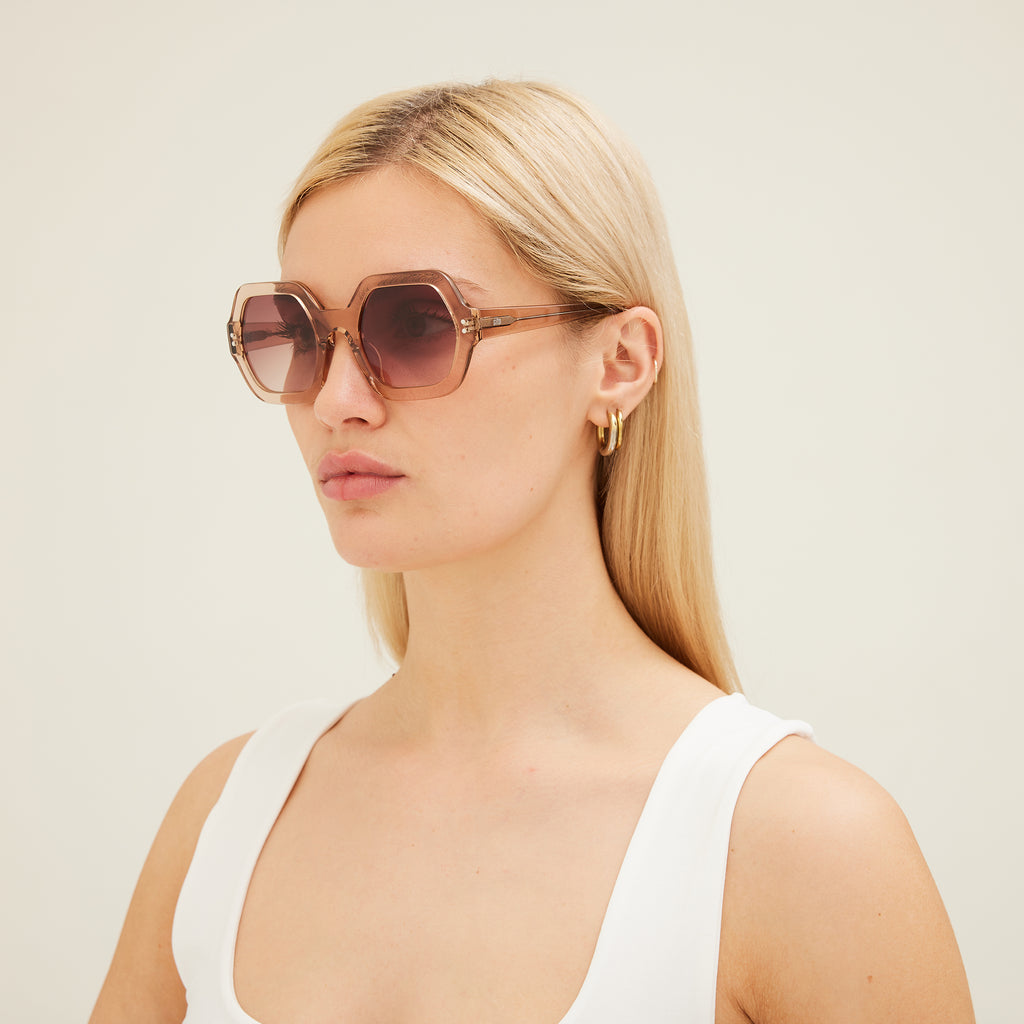 Woman wearing pink sunglasses with gradient lenses on a white background