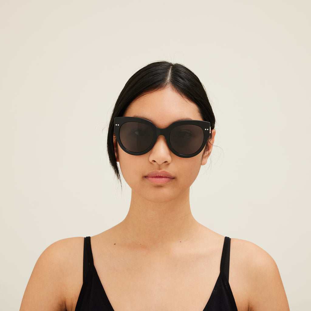 Woman wearing black sunglasses with dark lenses on a white background