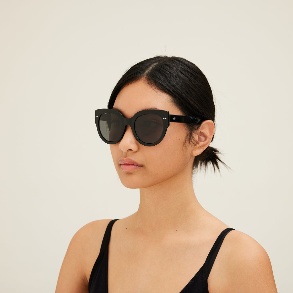 Woman wearing black sunglasses with dark lenses on a white background