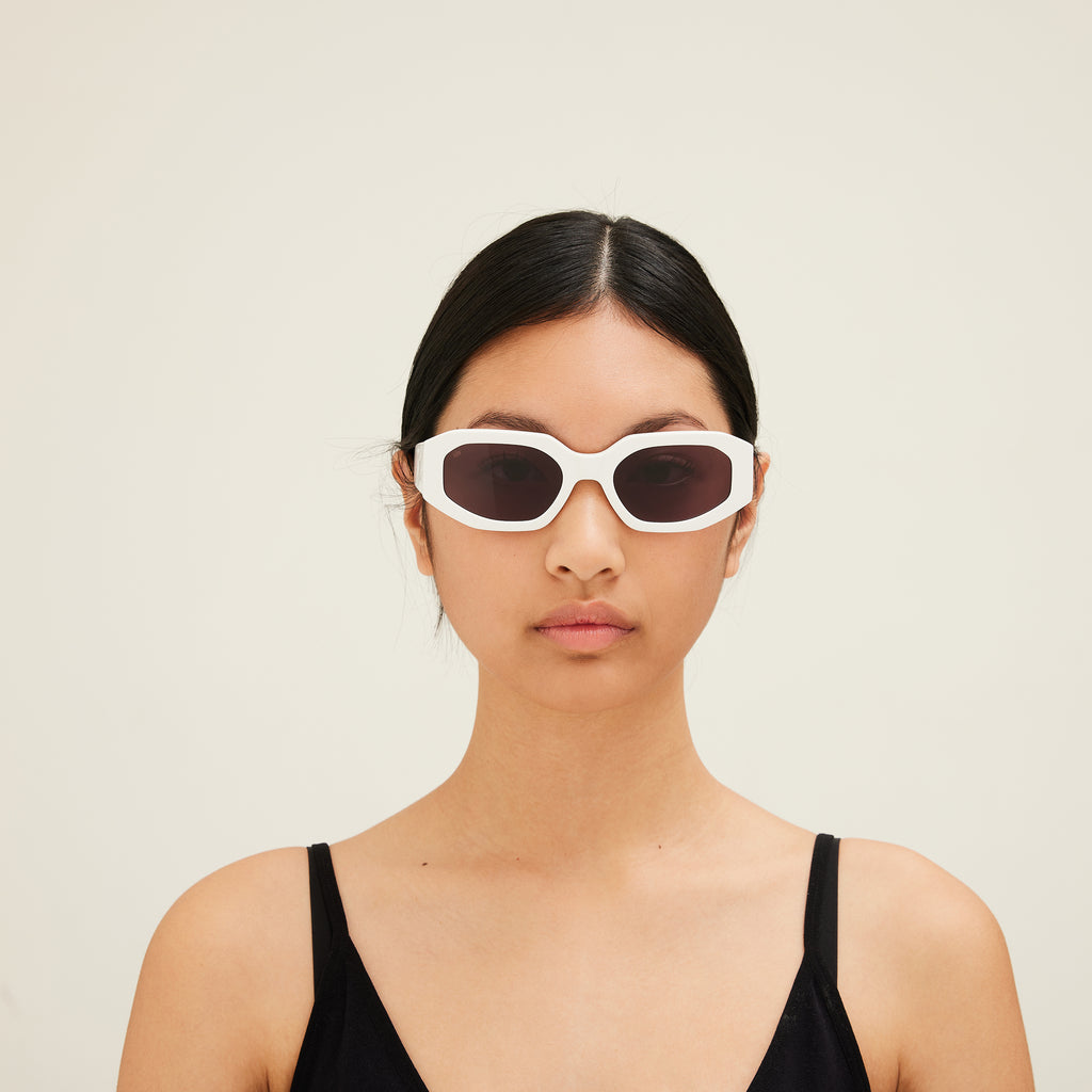 Person wearing white sunglasses with a plain background