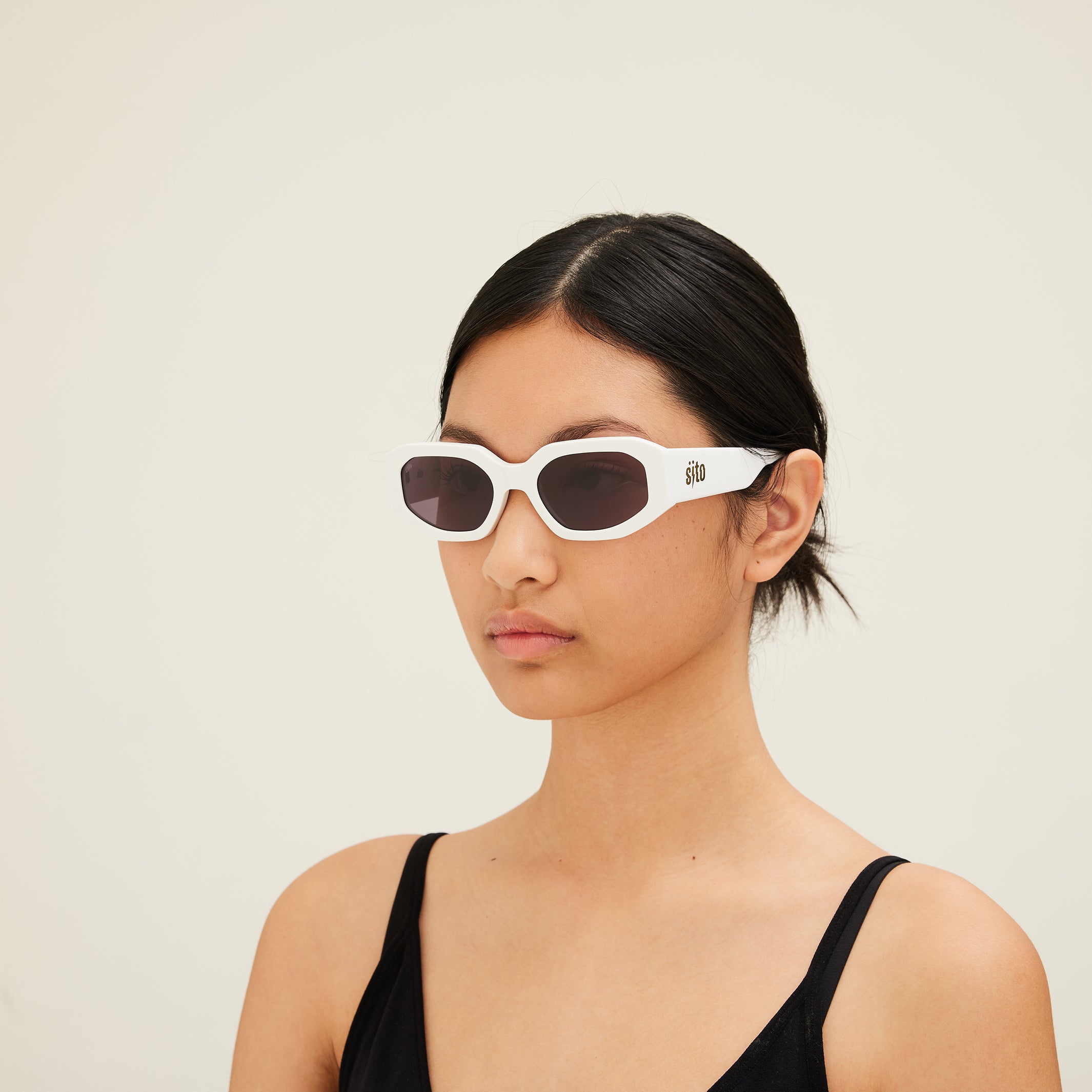 Woman wearing white sunglasses with a neutral background