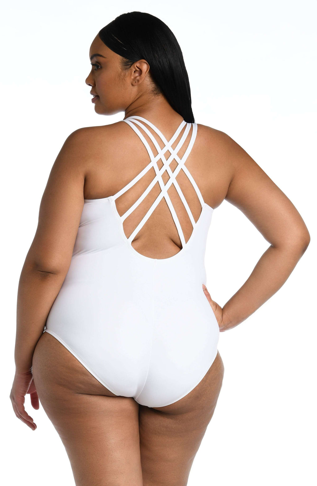 Woman wearing a white one-piece swimsuit with criss-cross back design on a white background