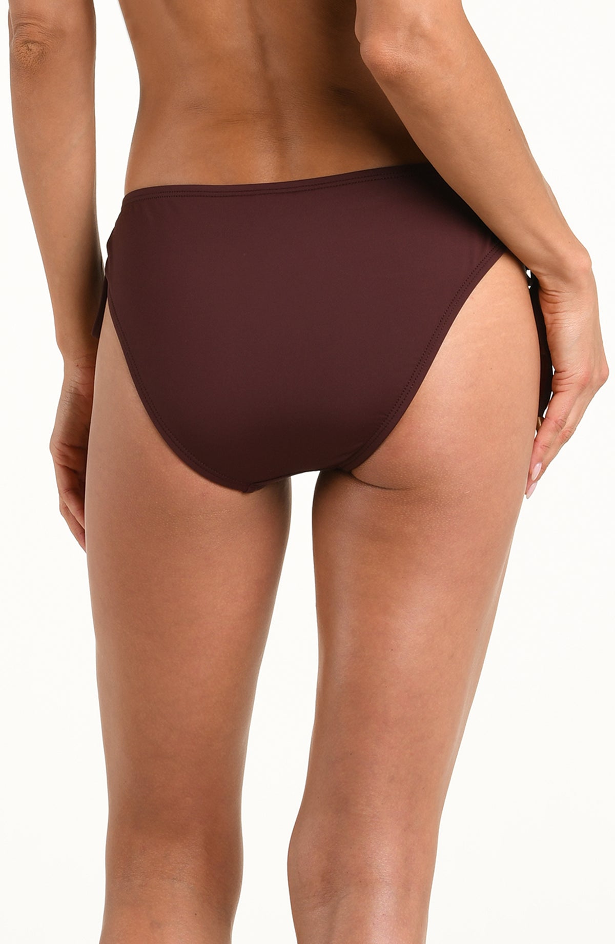 Woman wearing a solid java brown bikini bottom with adjustable loop sides against a white background. 