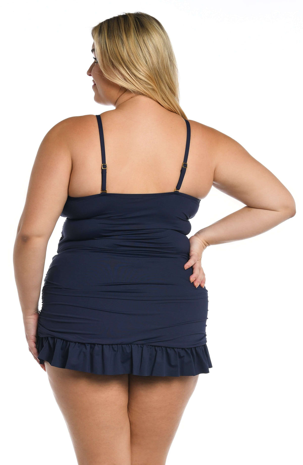 Woman wearing an indigo blue tankini top and matching swim skirt with a white background