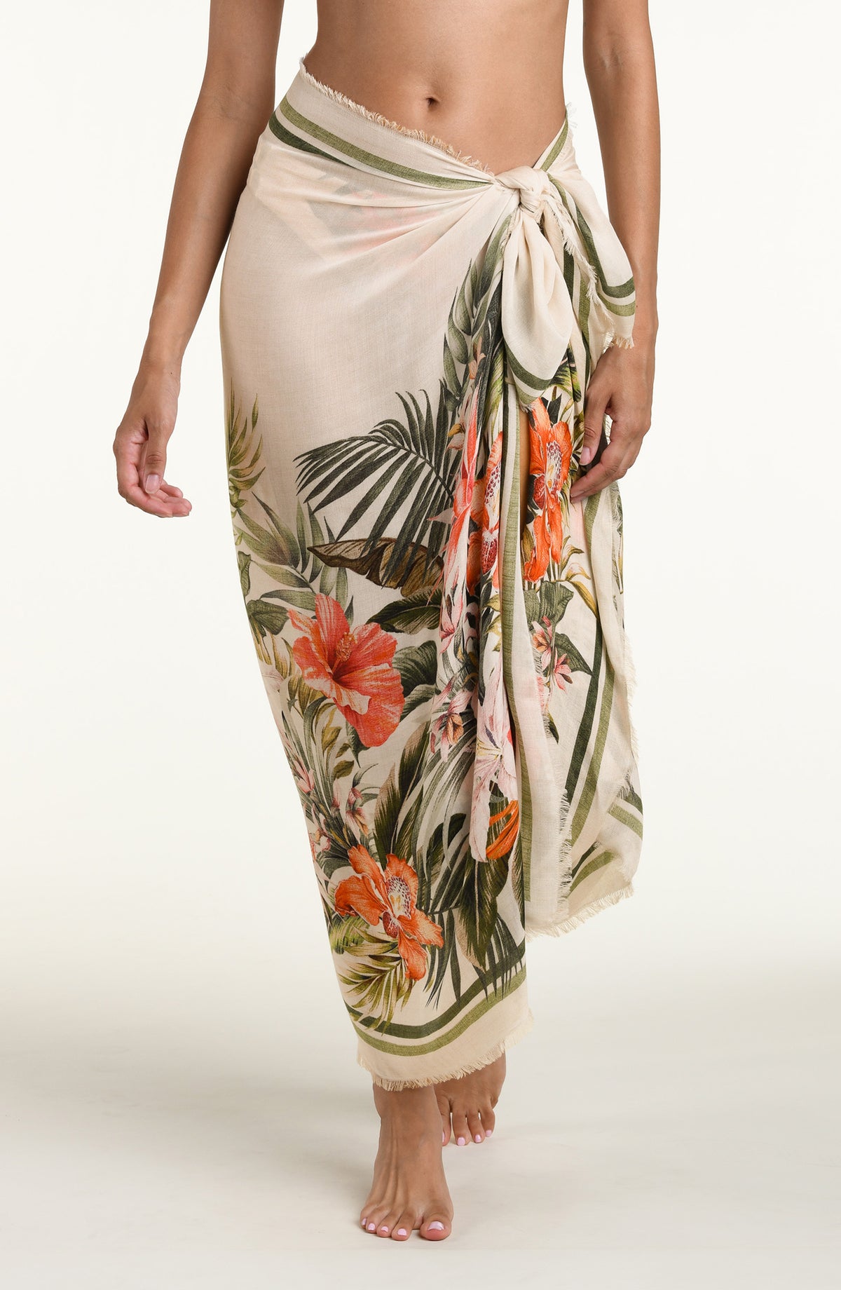 Woman wearing a white multicolored pareo wrap cover up against a white background. 
