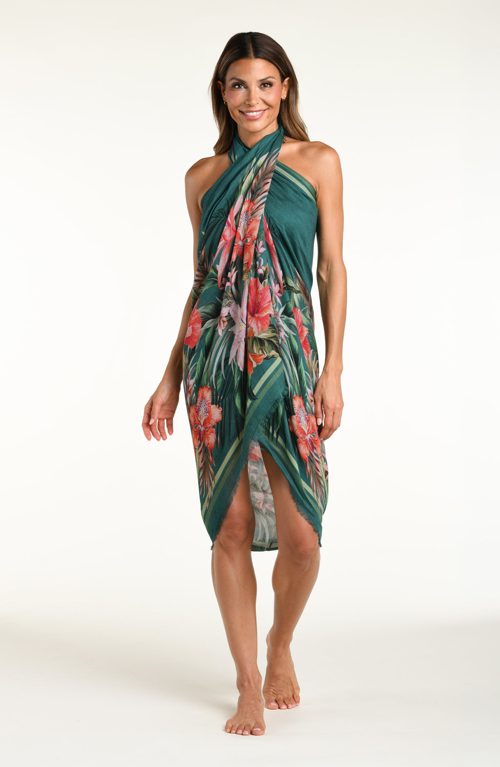 A model wearing a dark teal green tropical printed canga wrap skirt with a side slit, shown from the waist down against a white background.