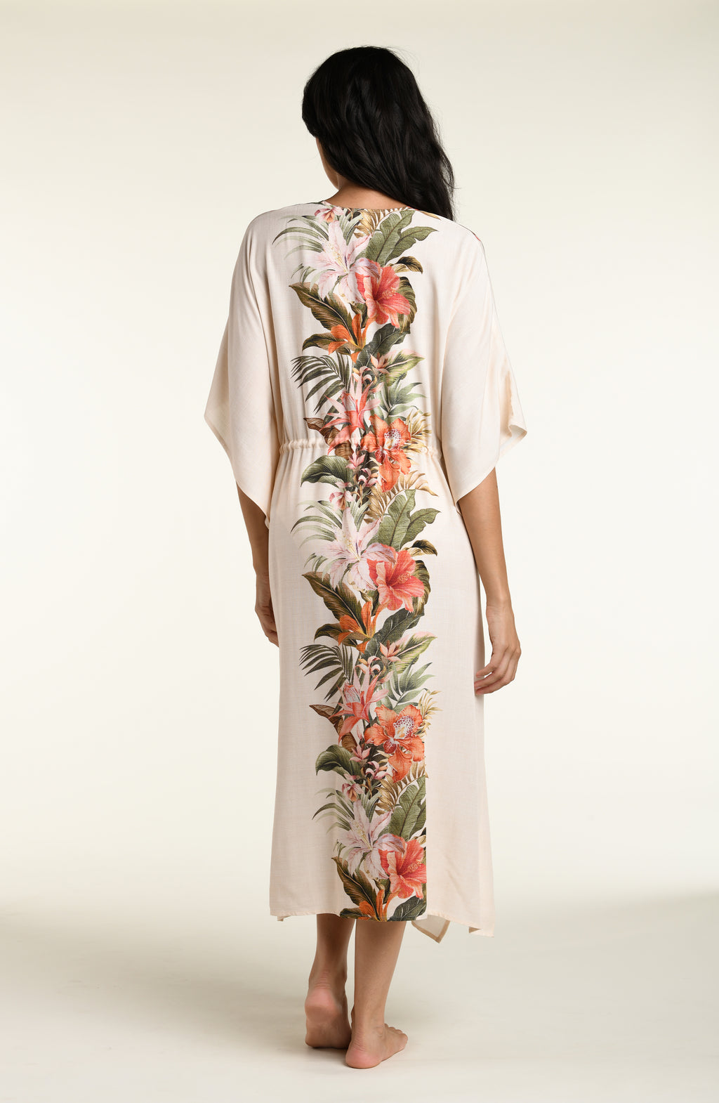 Woman wearing a champagne multicolored kimono cover up against a white background. 