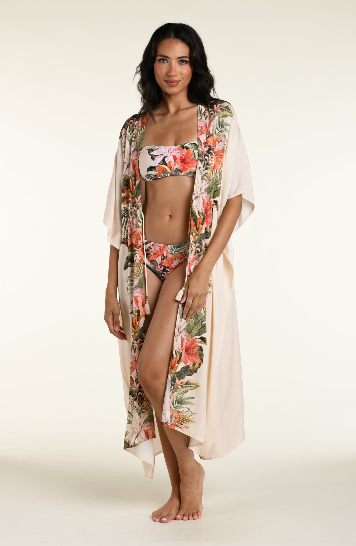 Woman wearing a champagne multicolored kimono cover up against a white background. 