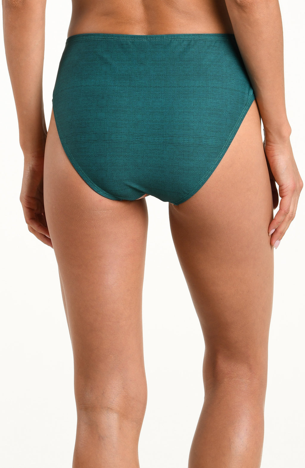 A model wearing high-waisted bikini bottoms with a tropical floral print on a teal green background, featuring pink, orange, and white flowers with green leaves.