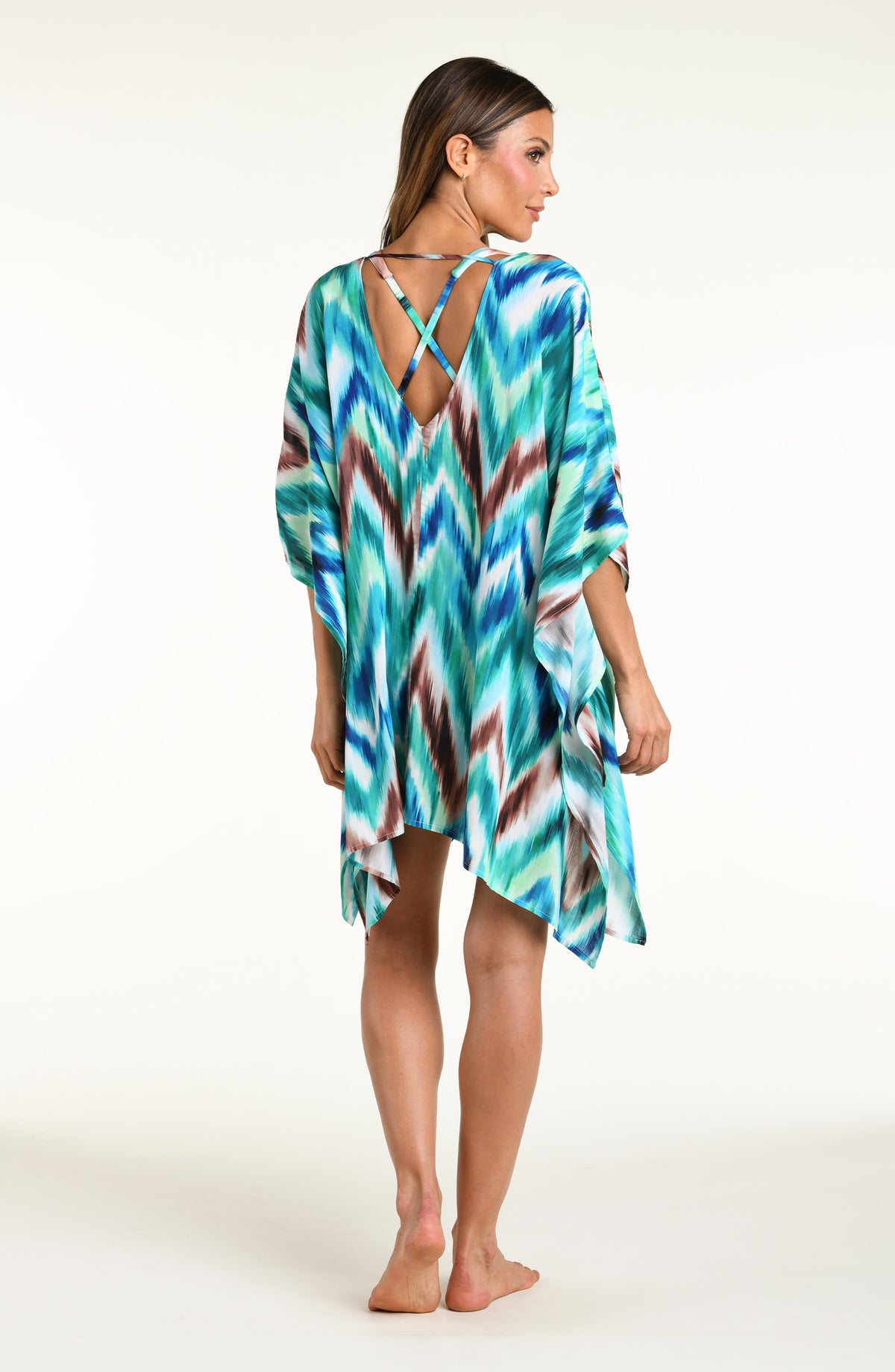 Woman wearing a teal multicolored tunic cover up against a white background. 