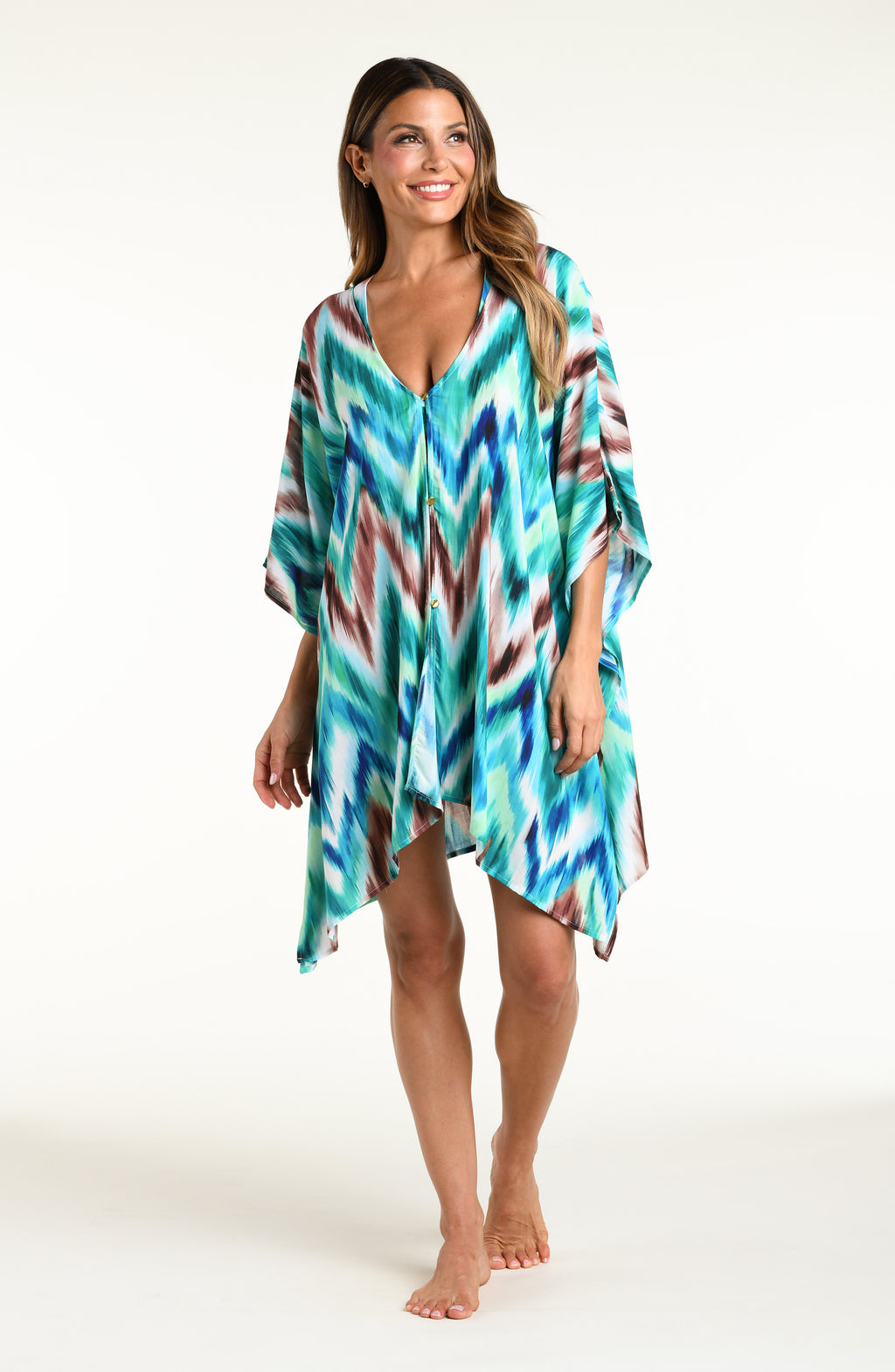 Woman wearing a teal multicolored tunic cover up against a white background. 