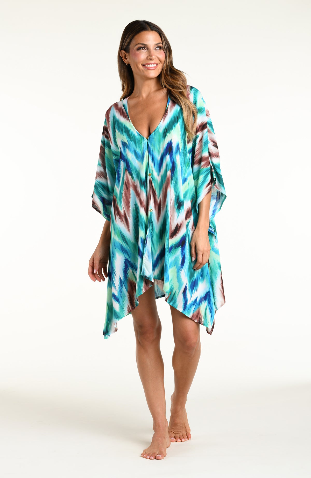Woman wearing a teal multicolored tunic cover up against a white background. 