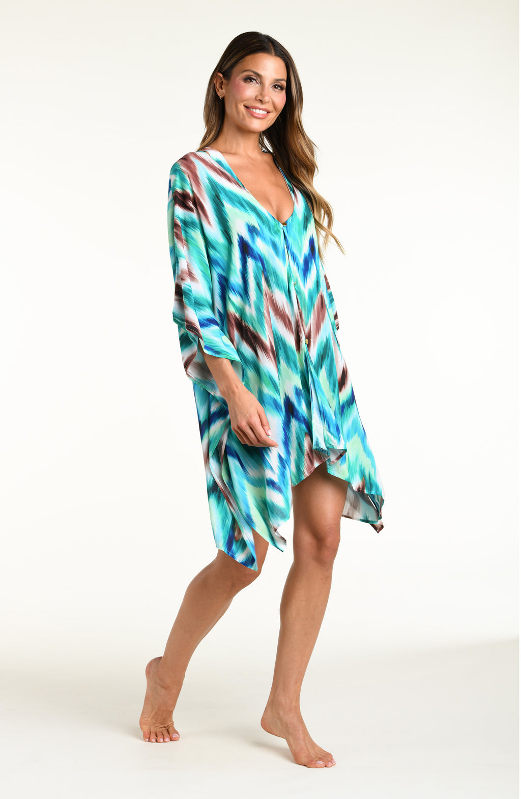 Woman wearing a teal multicolored tunic cover up against a white background. 