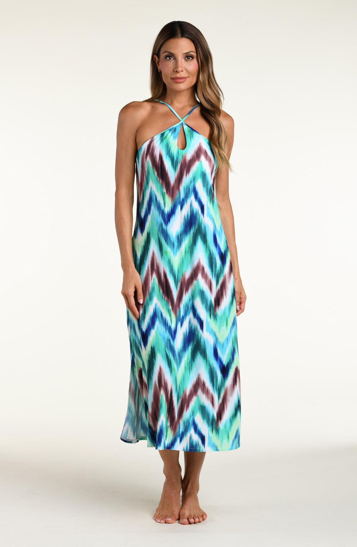 Woman wearing a multicolored teal midi dress cover up against a white background. 