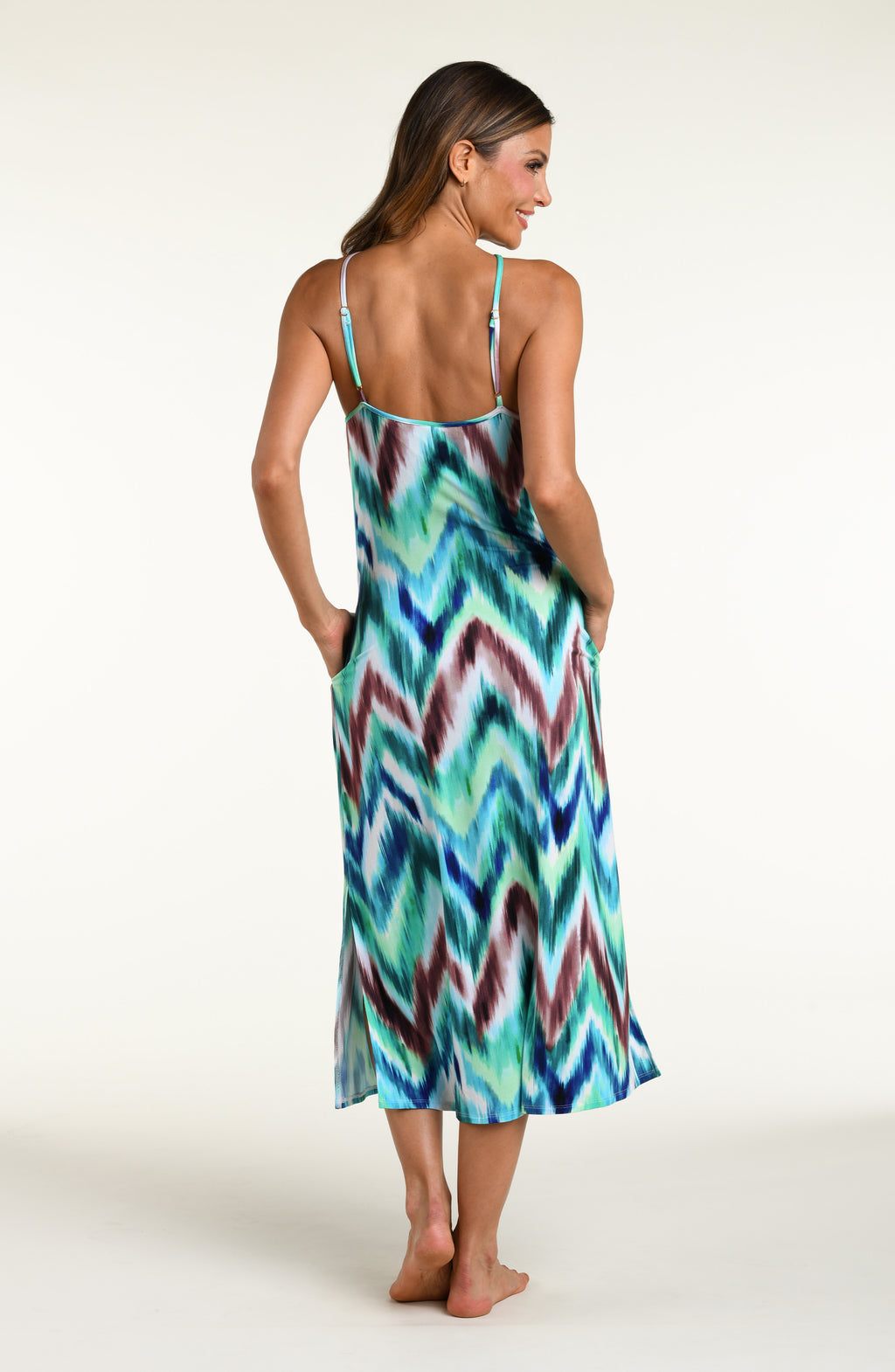Woman wearing a multicolored teal midi dress cover up against a white background. 
