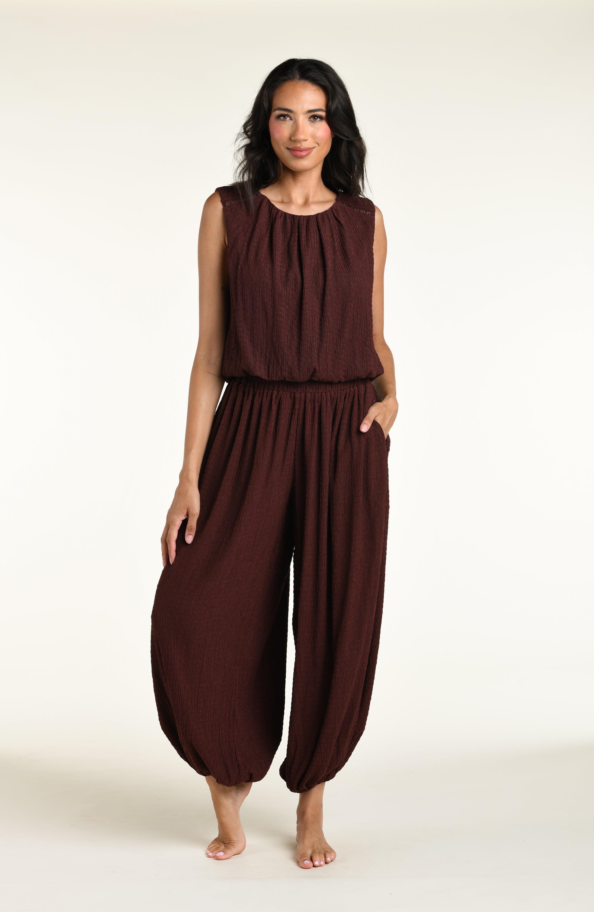 Woman wearing a java brown colored sleeveless top and matching pants against a white background. 
