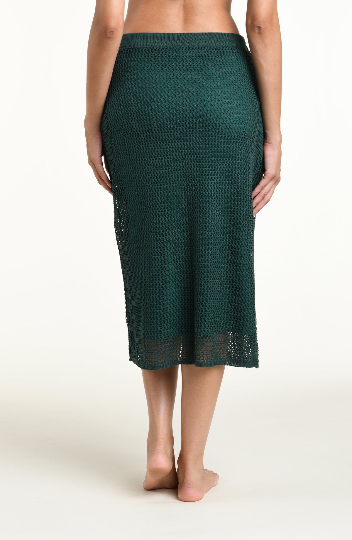 Woman wearing a jungle green crochet midi skirt against a white background. 