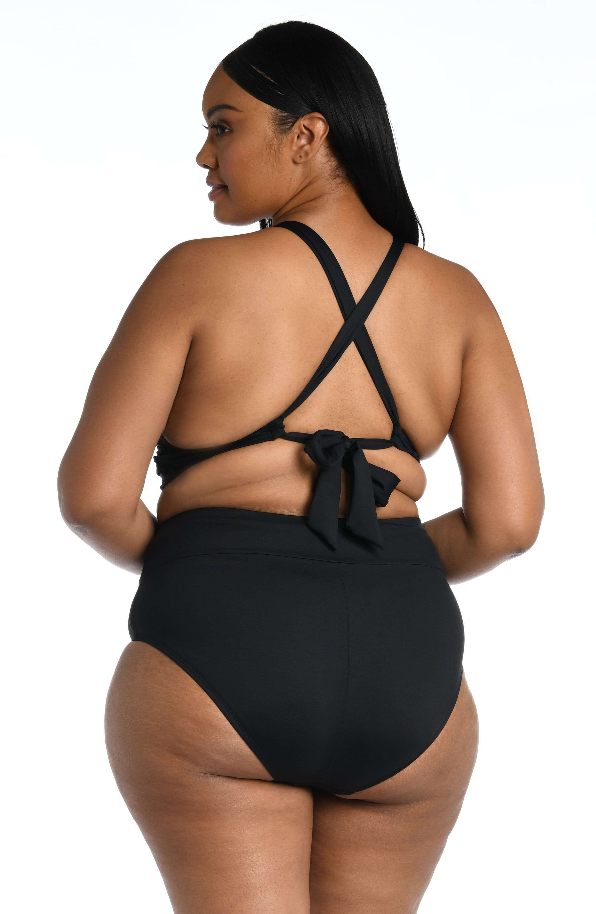 Woman wearing a black midkini top and matching bottom against a white background. 