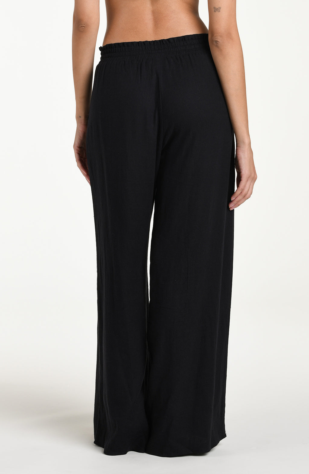 Black wide-leg pants with gold buttons against a white background