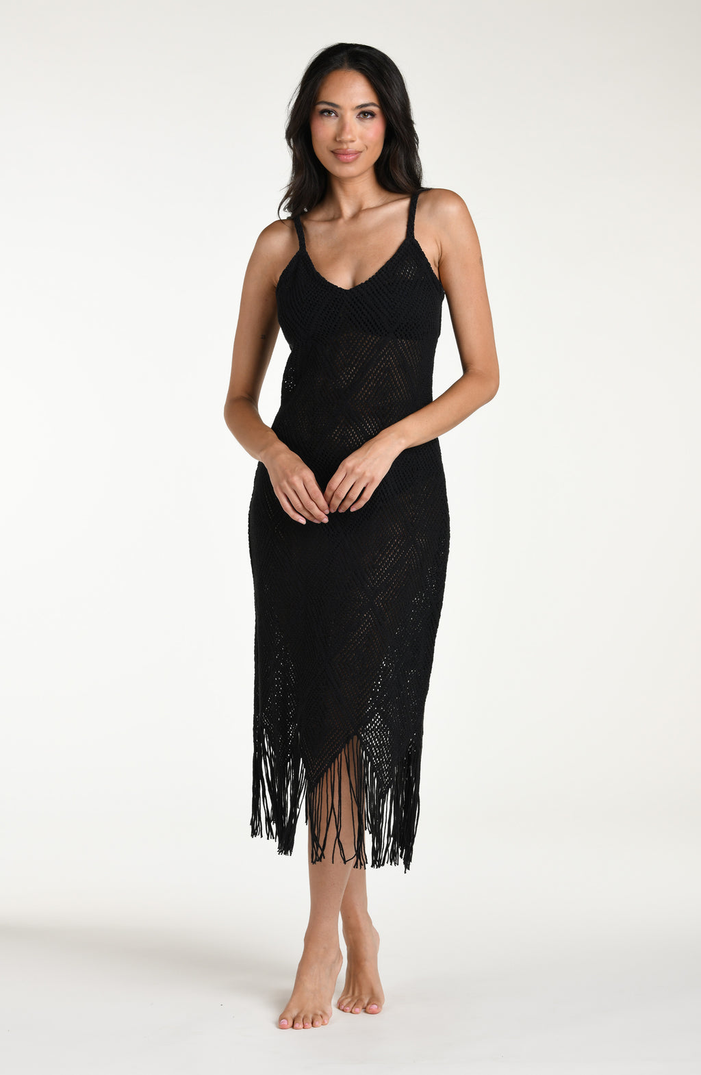 Woman wearing a black cover  up dress with fringe details against a white background.
