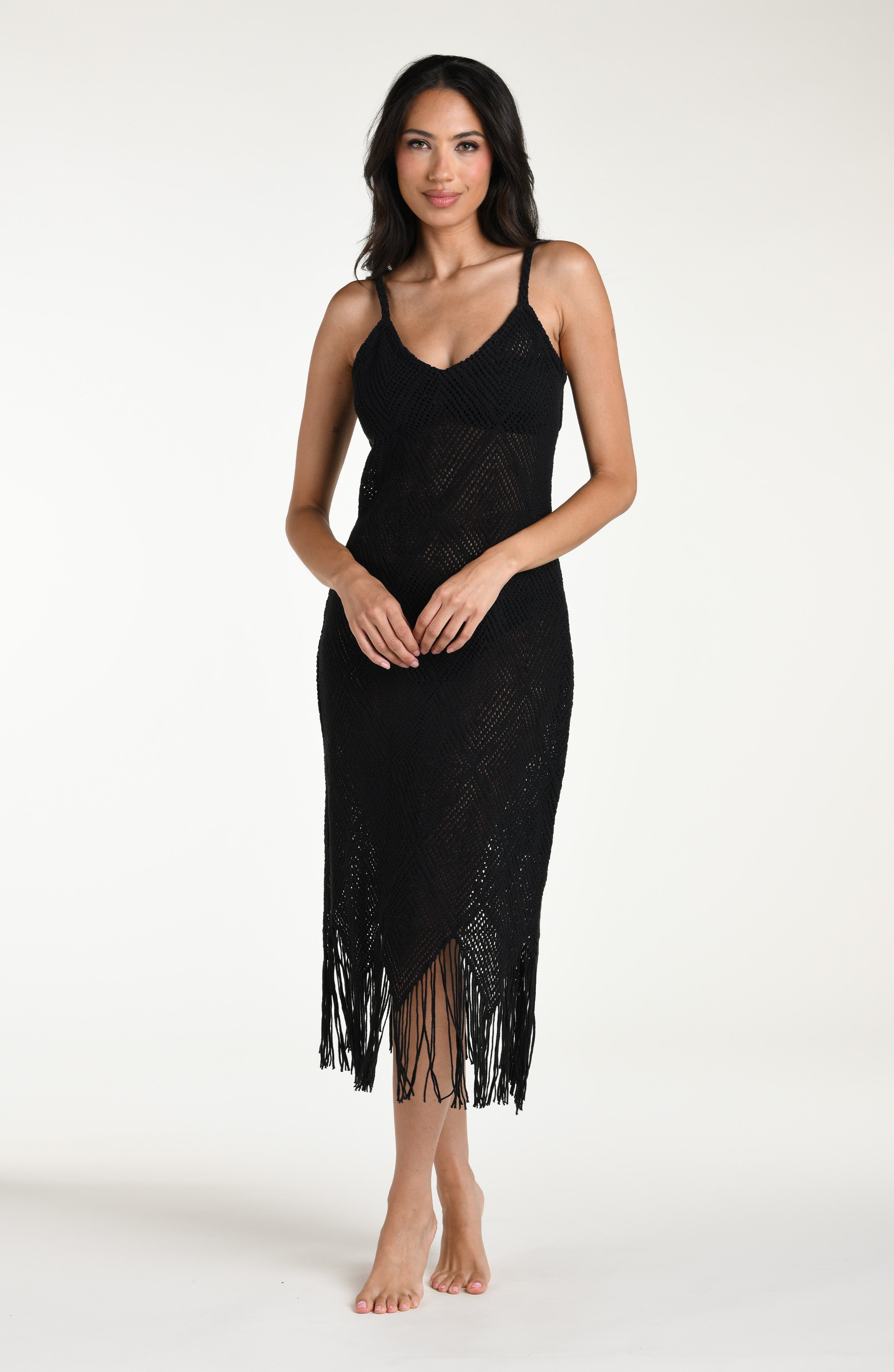 Woman wearing a black cover  up dress with fringe details against a white background.