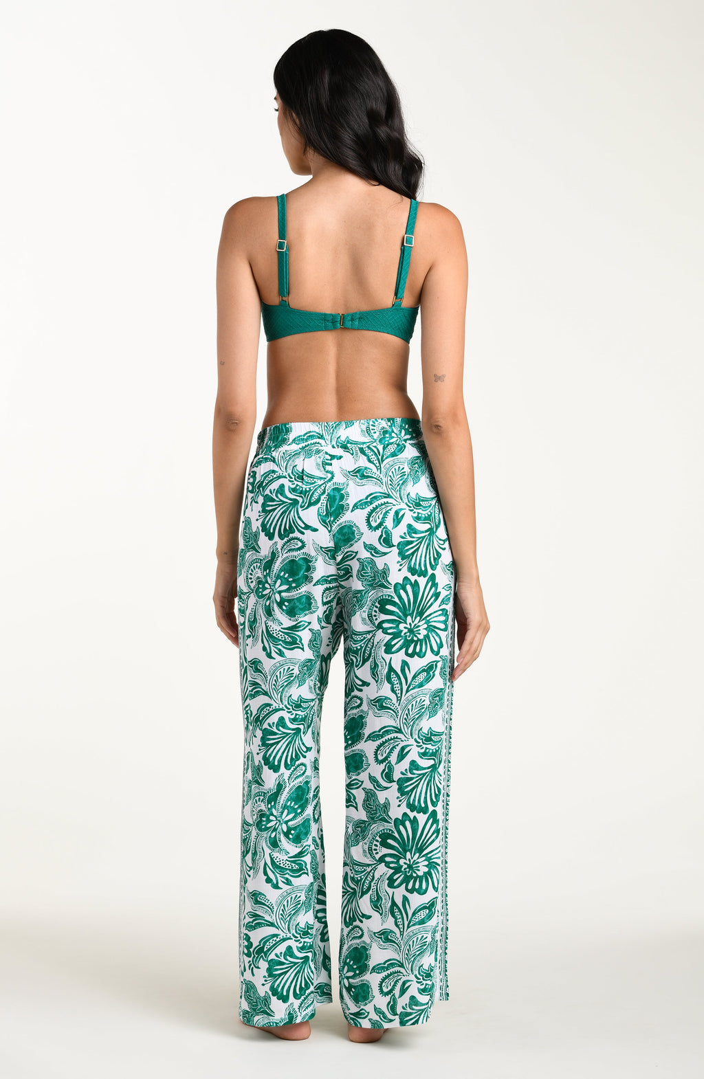 Woman wearing a green floral patterned pants on a white background