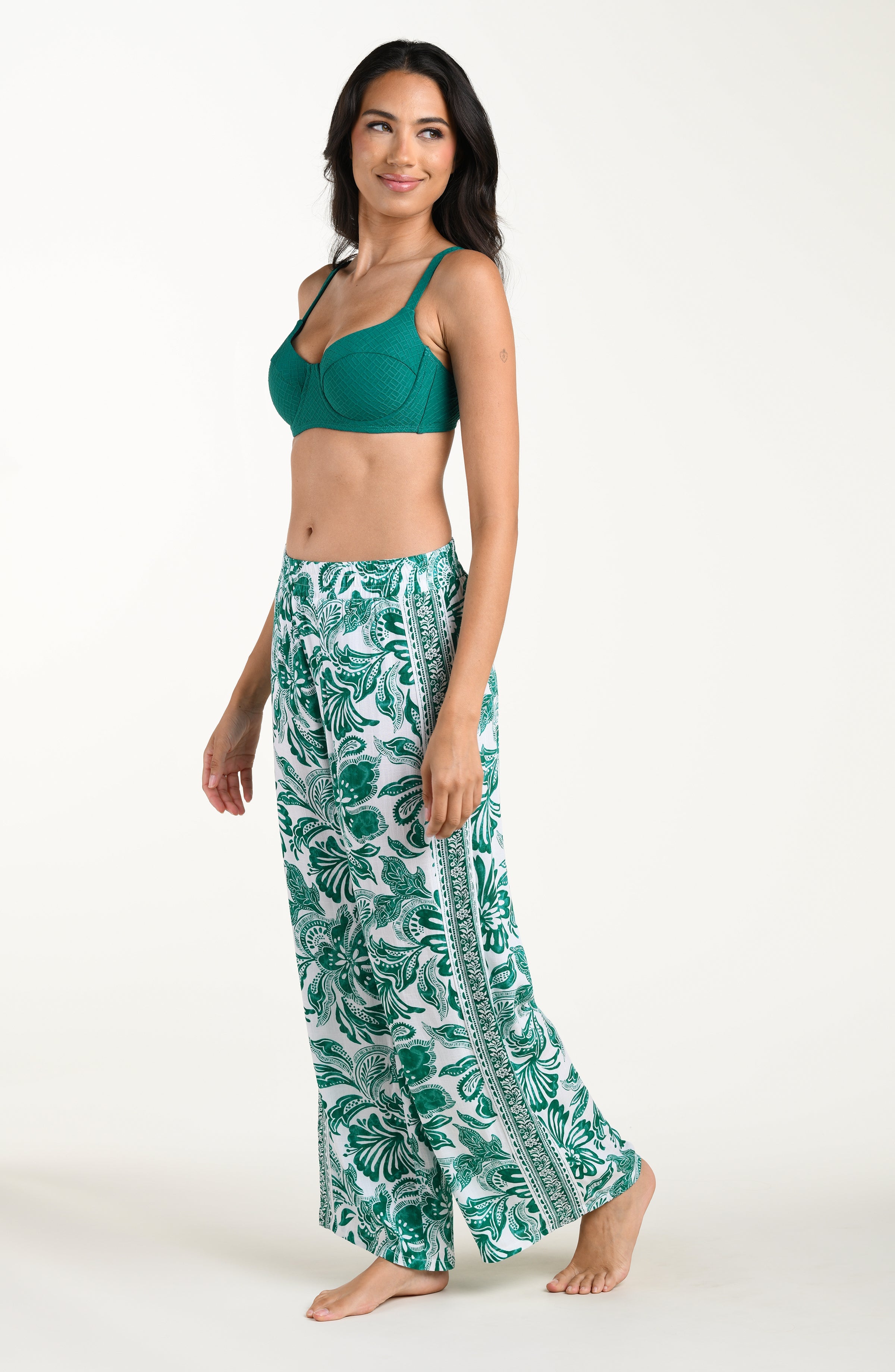 Woman wearing a green top and leaf-patterned pants on a white background