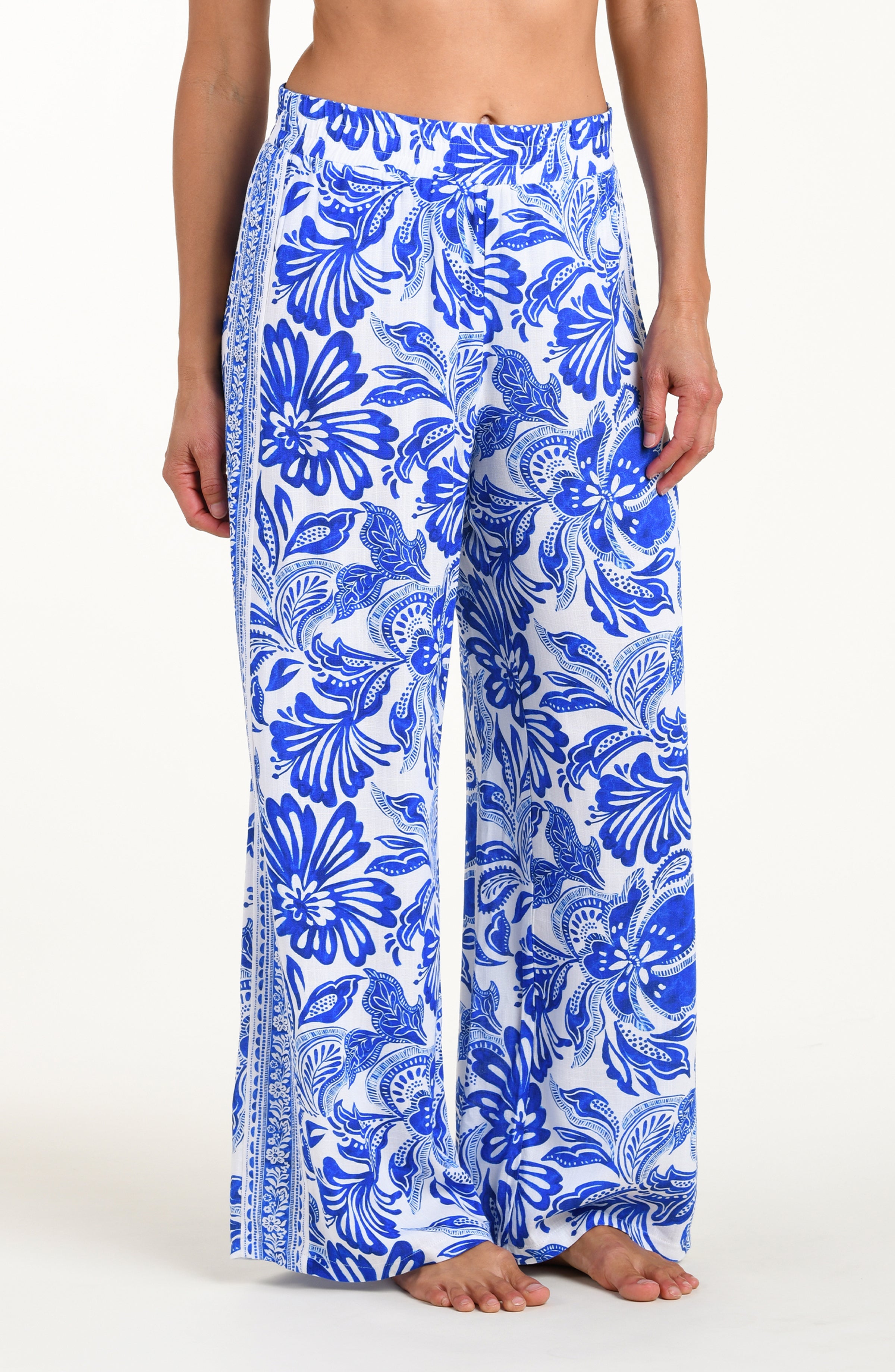 Person wearing blue floral patterned pants on a white background