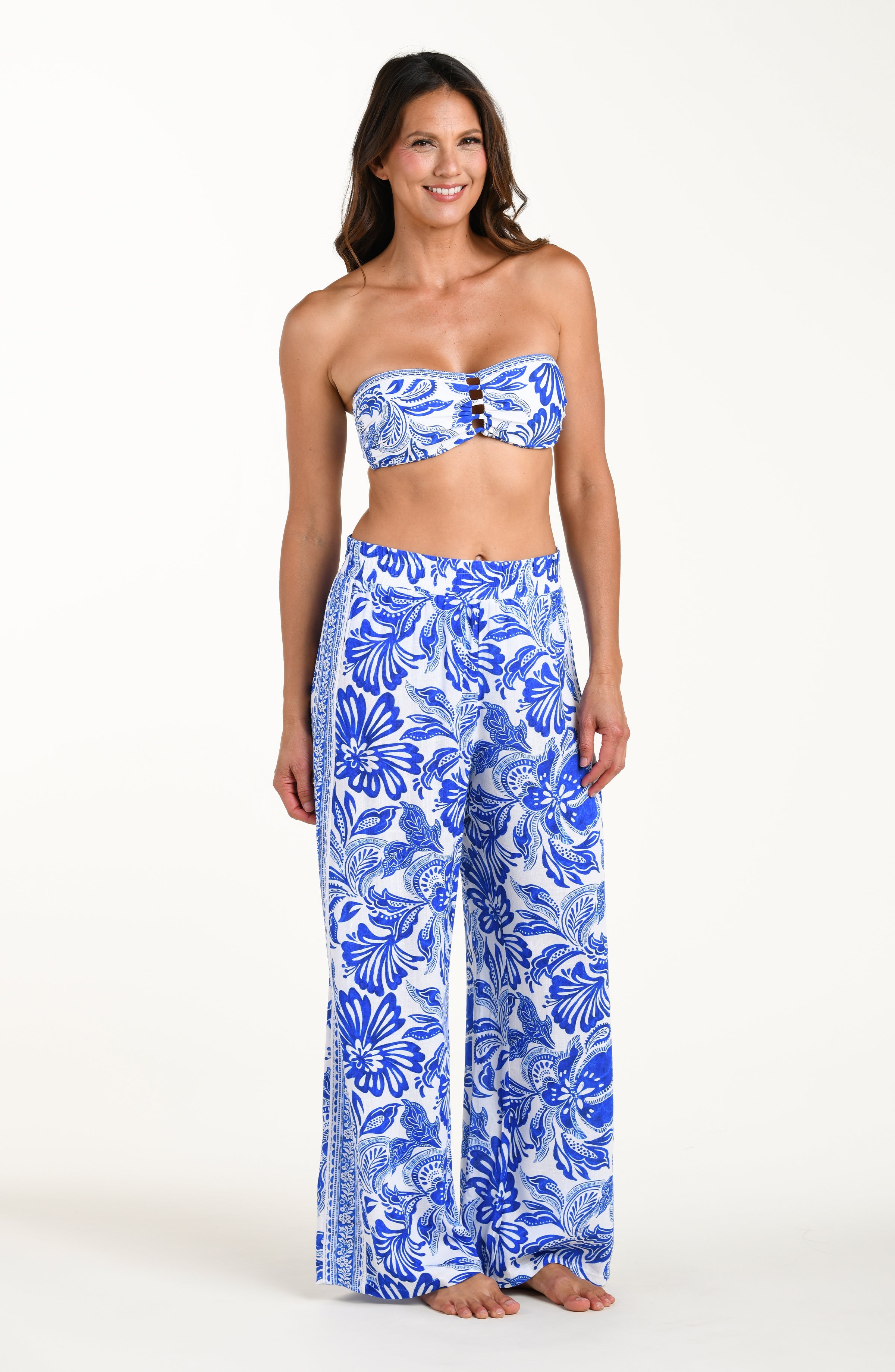Woman wearing a blue floral bikini top and wide-leg pants on a white background