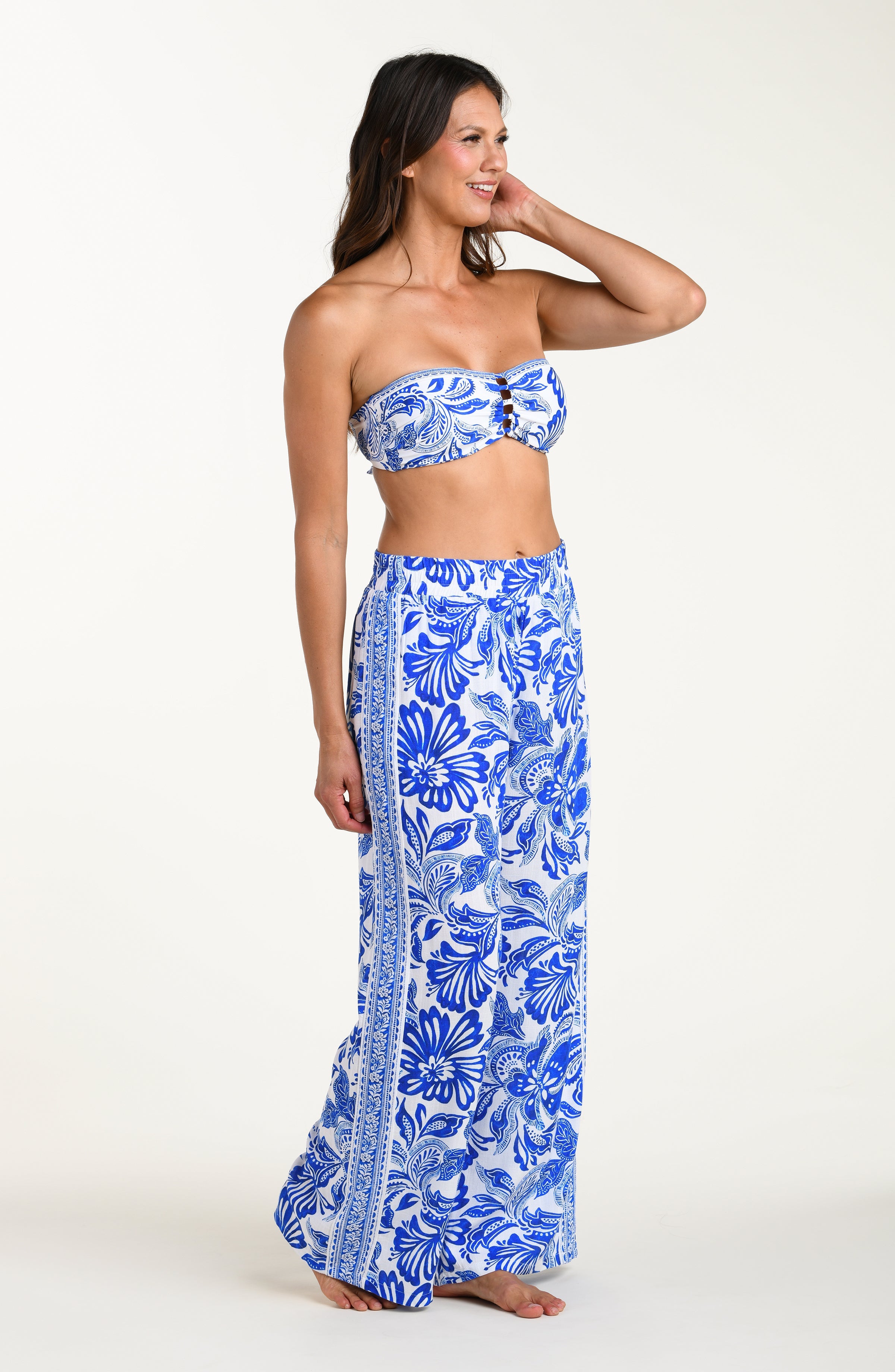 Woman wearing a blue floral bikini top and pants on a white background