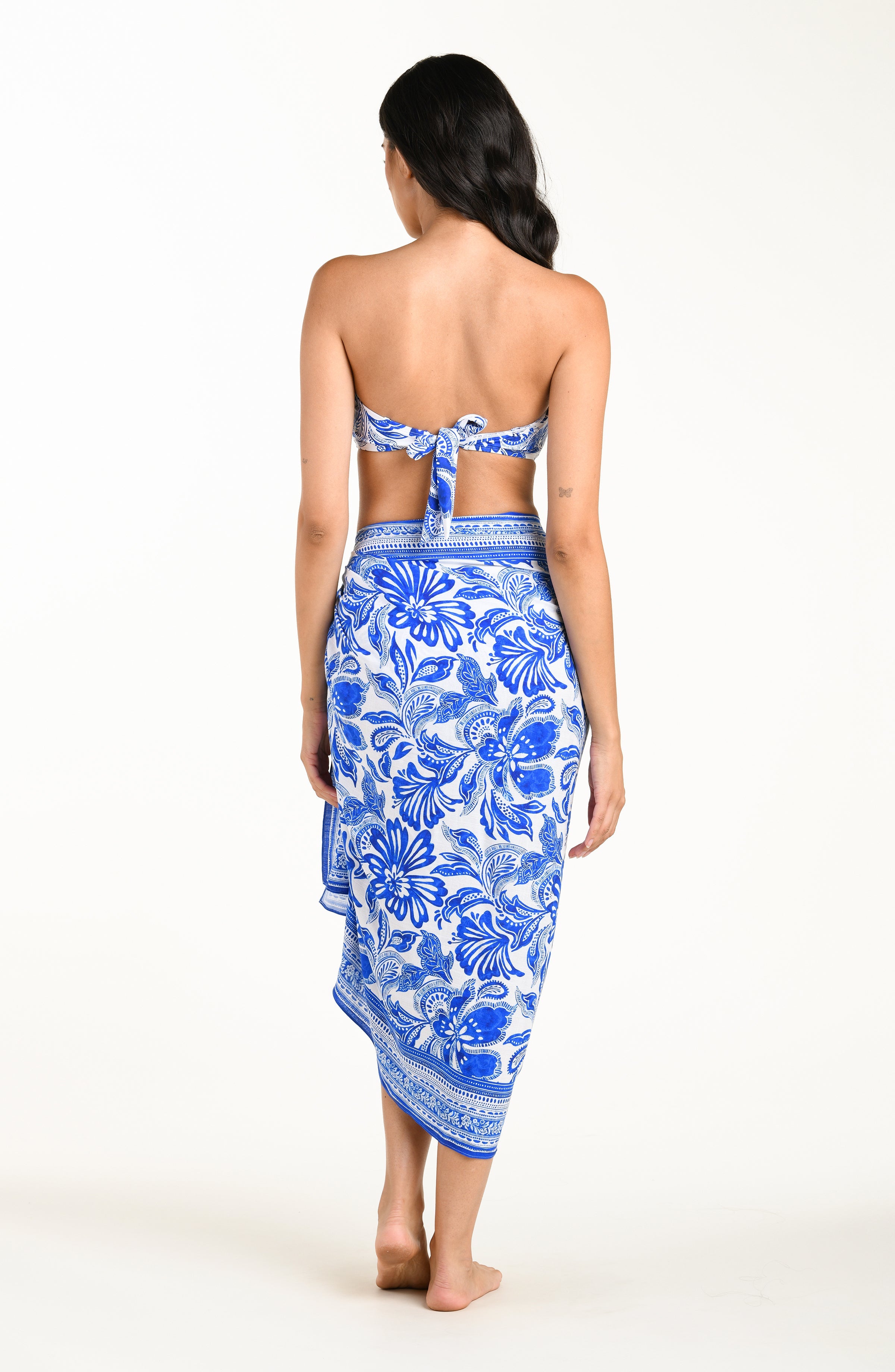 Woman wearing a blue and white floral sarong on a white background