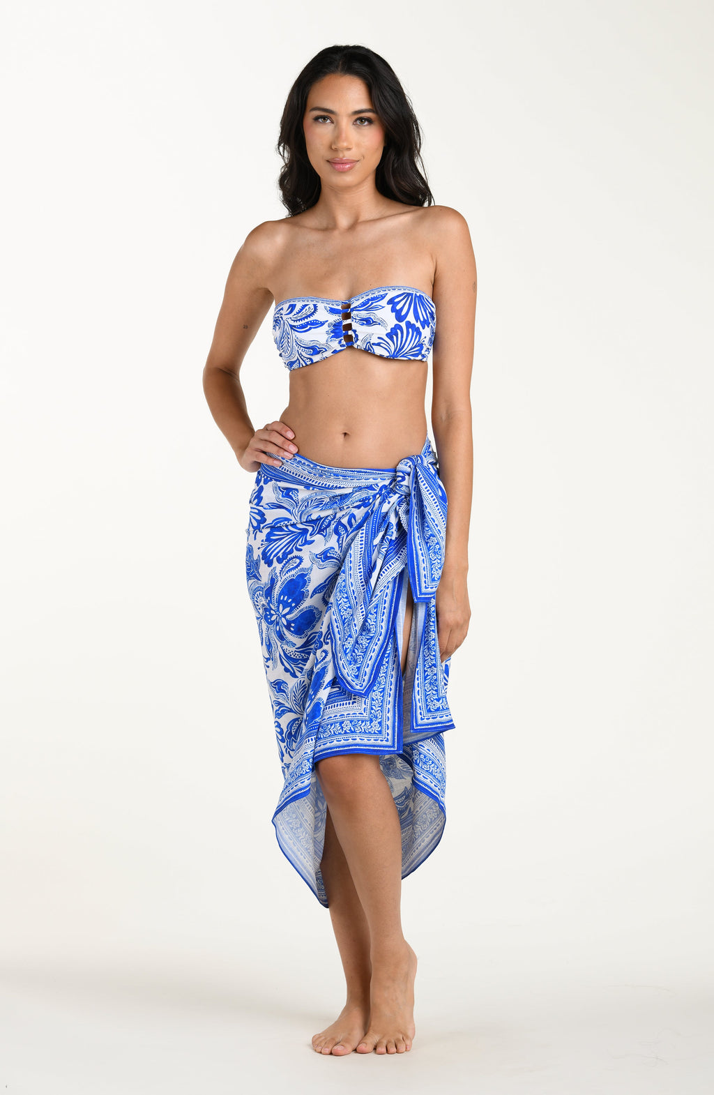 Woman wearing a blue and white patterned bikini top and sarong on a white background