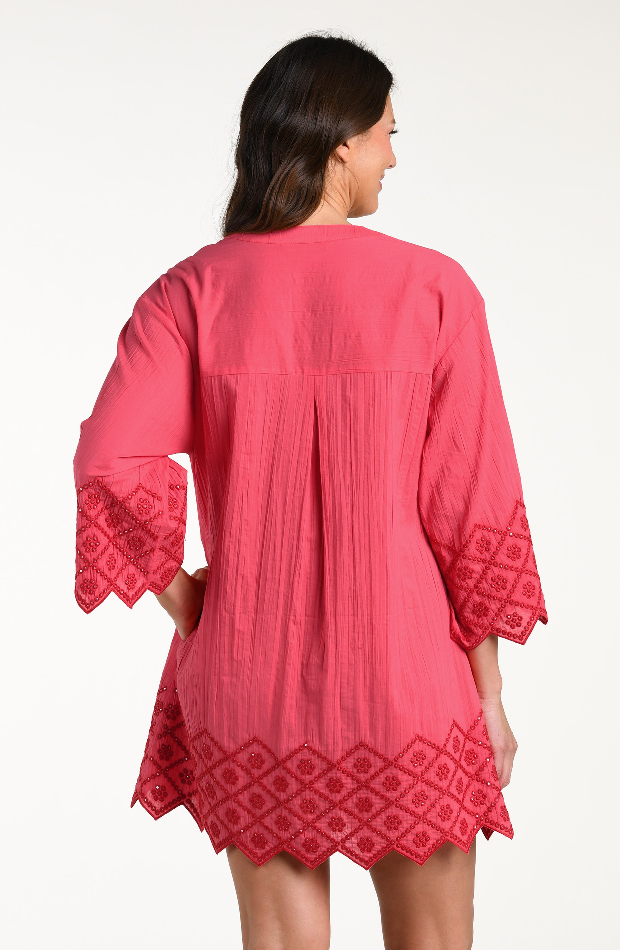 Woman wearing a guava colored V-neck tunic against a white background. 