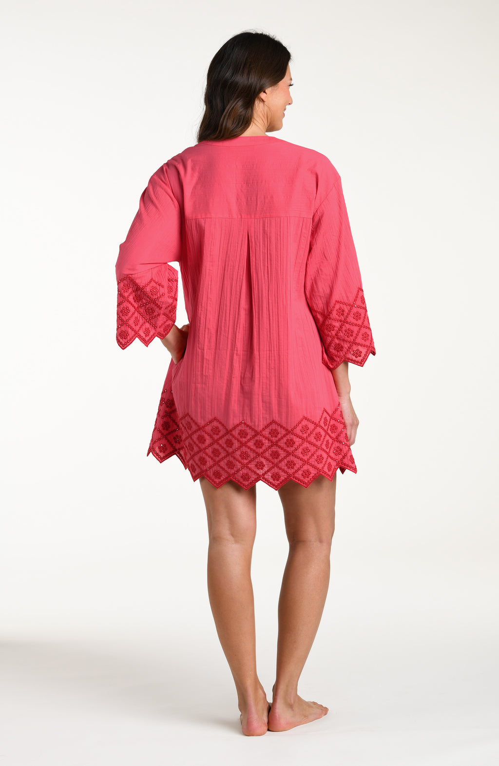 Woman wearing a guava colored V-neck tunic against a white background. 