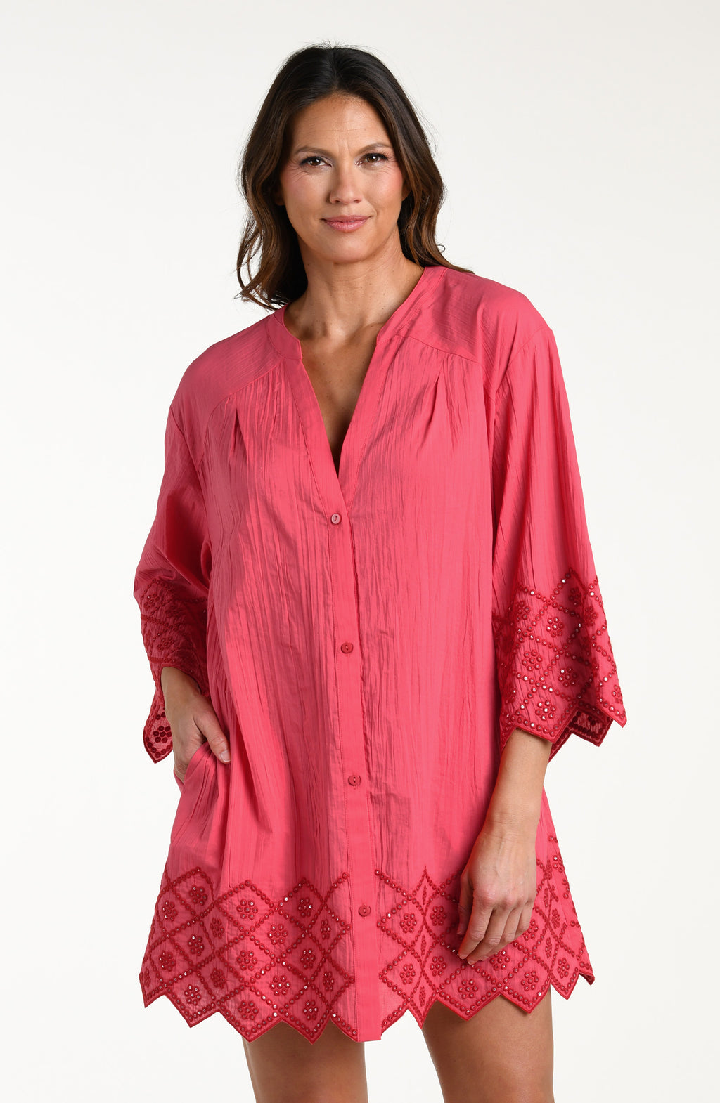 Woman wearing a guava colored V-neck tunic against a white background. 