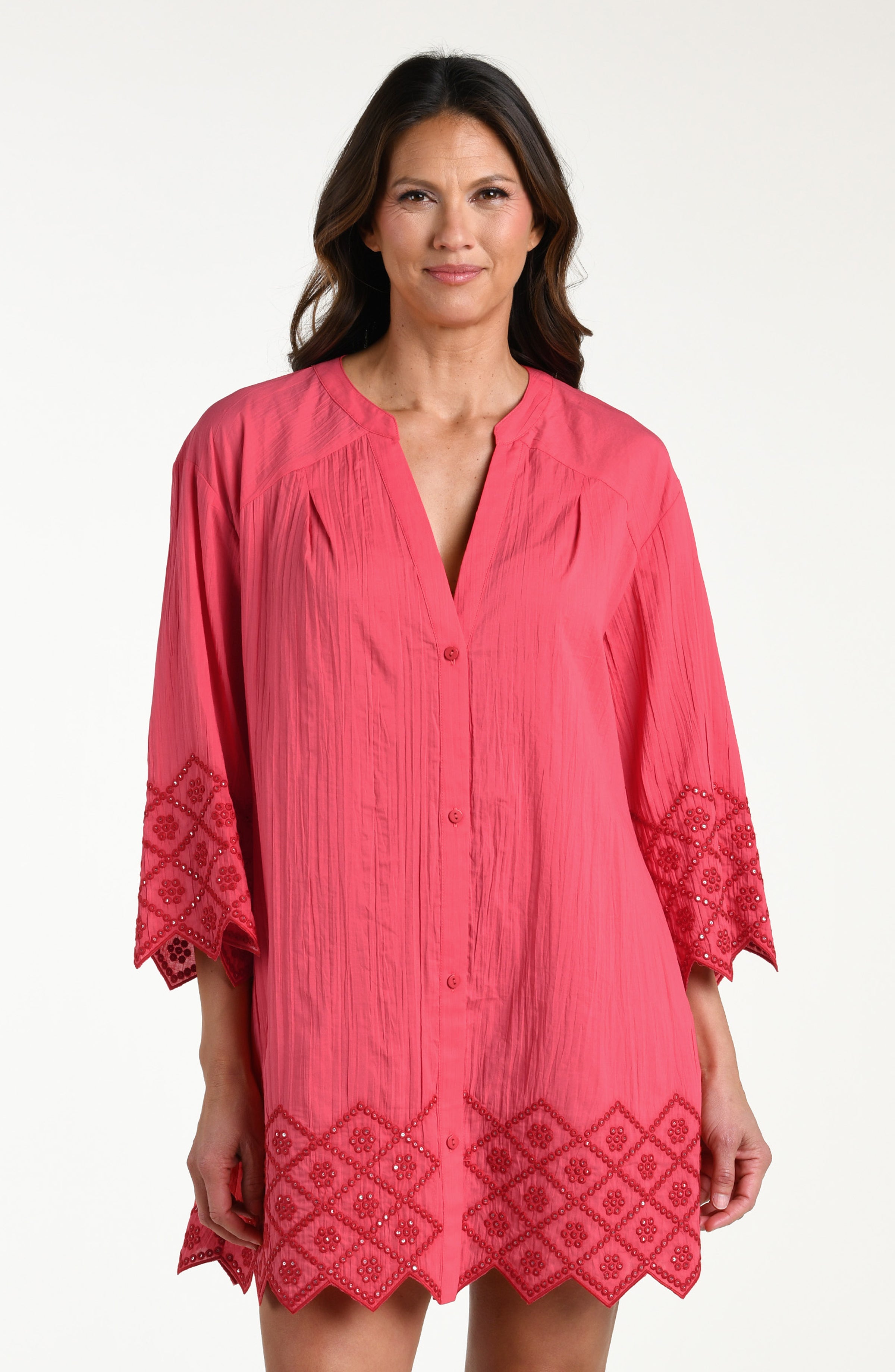 Woman wearing a guava colored V-neck tunic against a white background. 