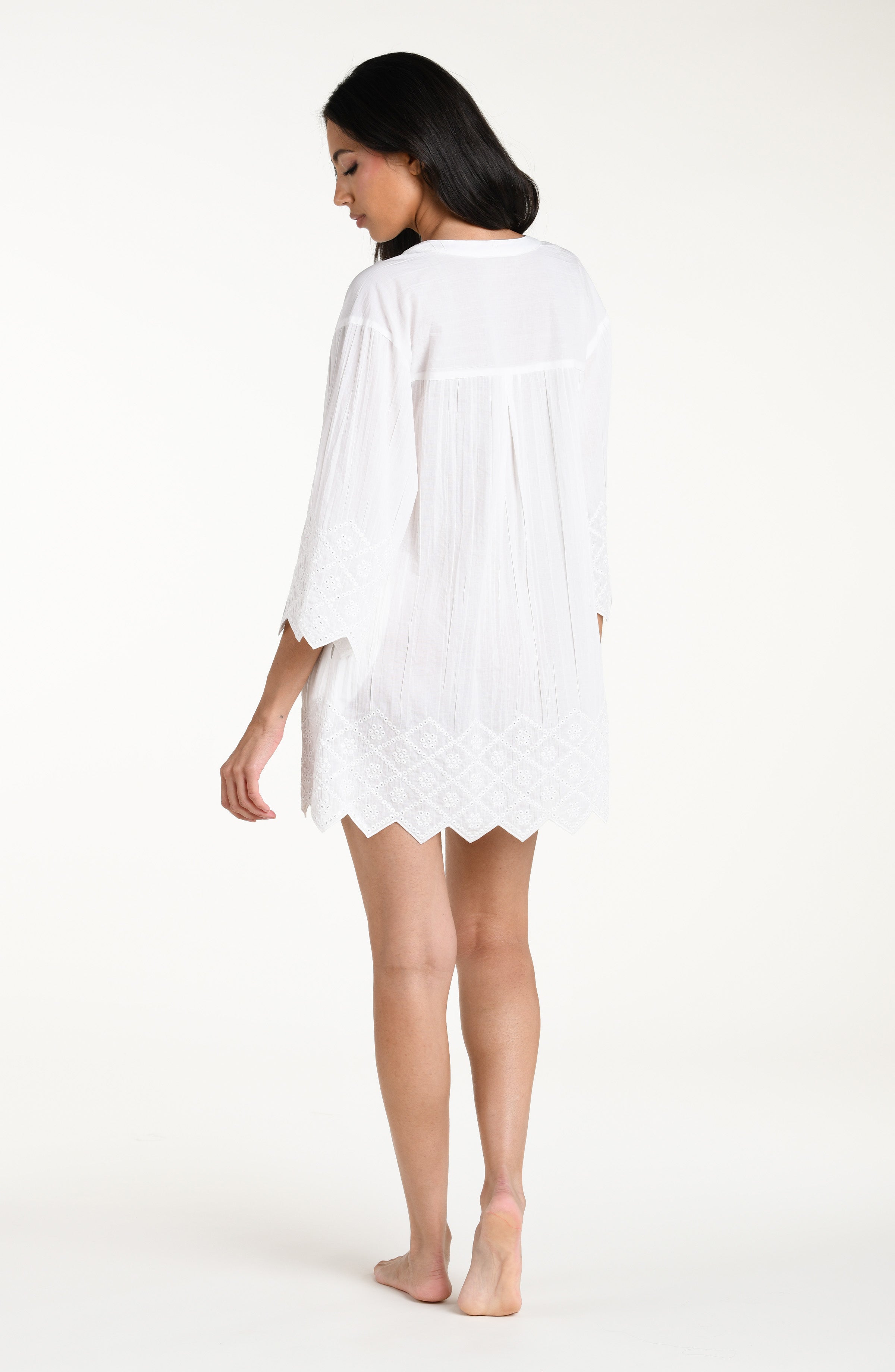 Woman wearing a white V-neck tunic against a white background