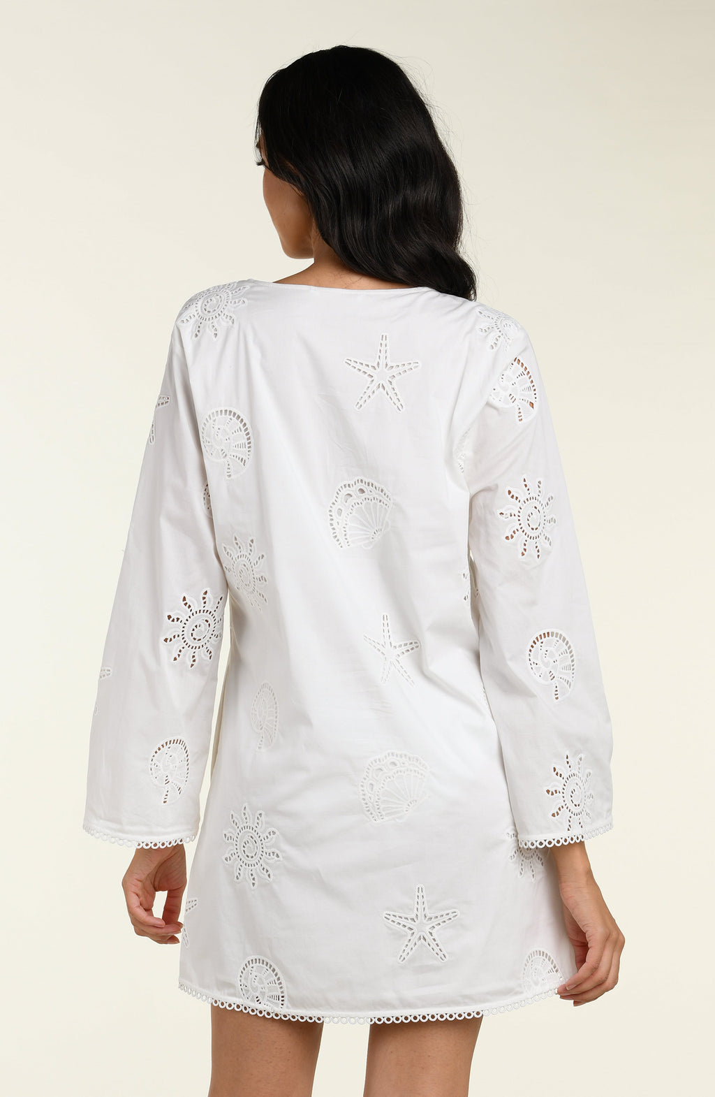 Woman wearing a white long sleeve tunic against a white background. 