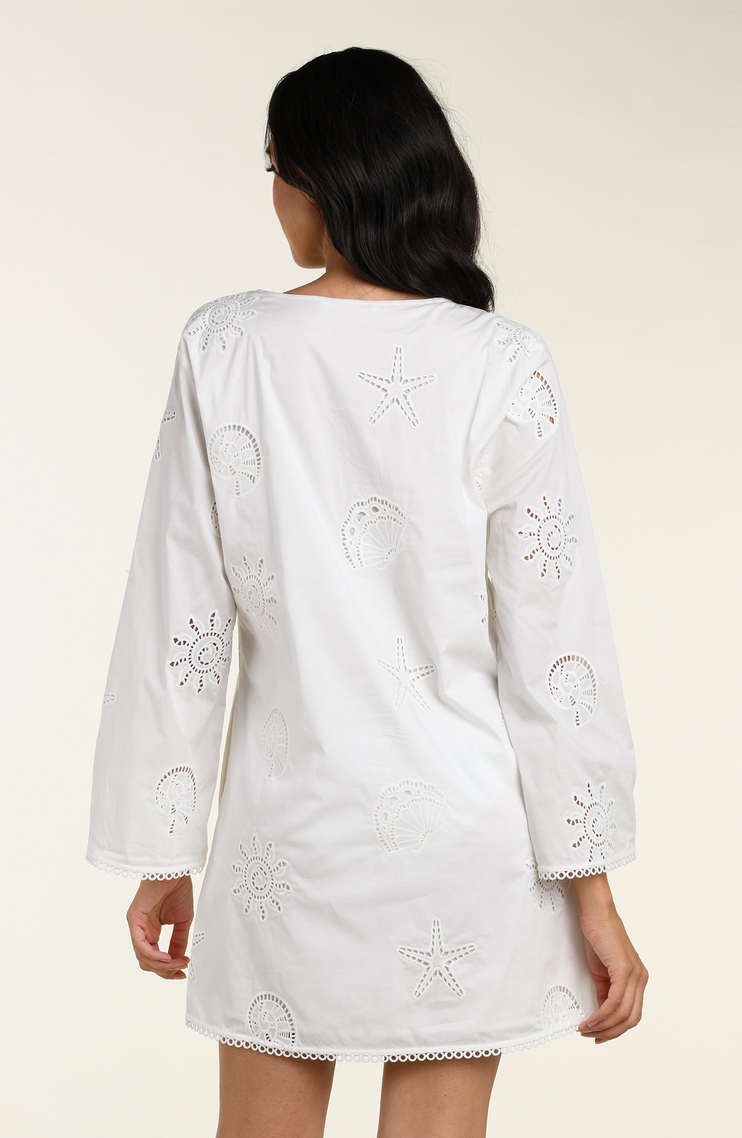 Woman wearing a white long sleeve tunic against a white background. 