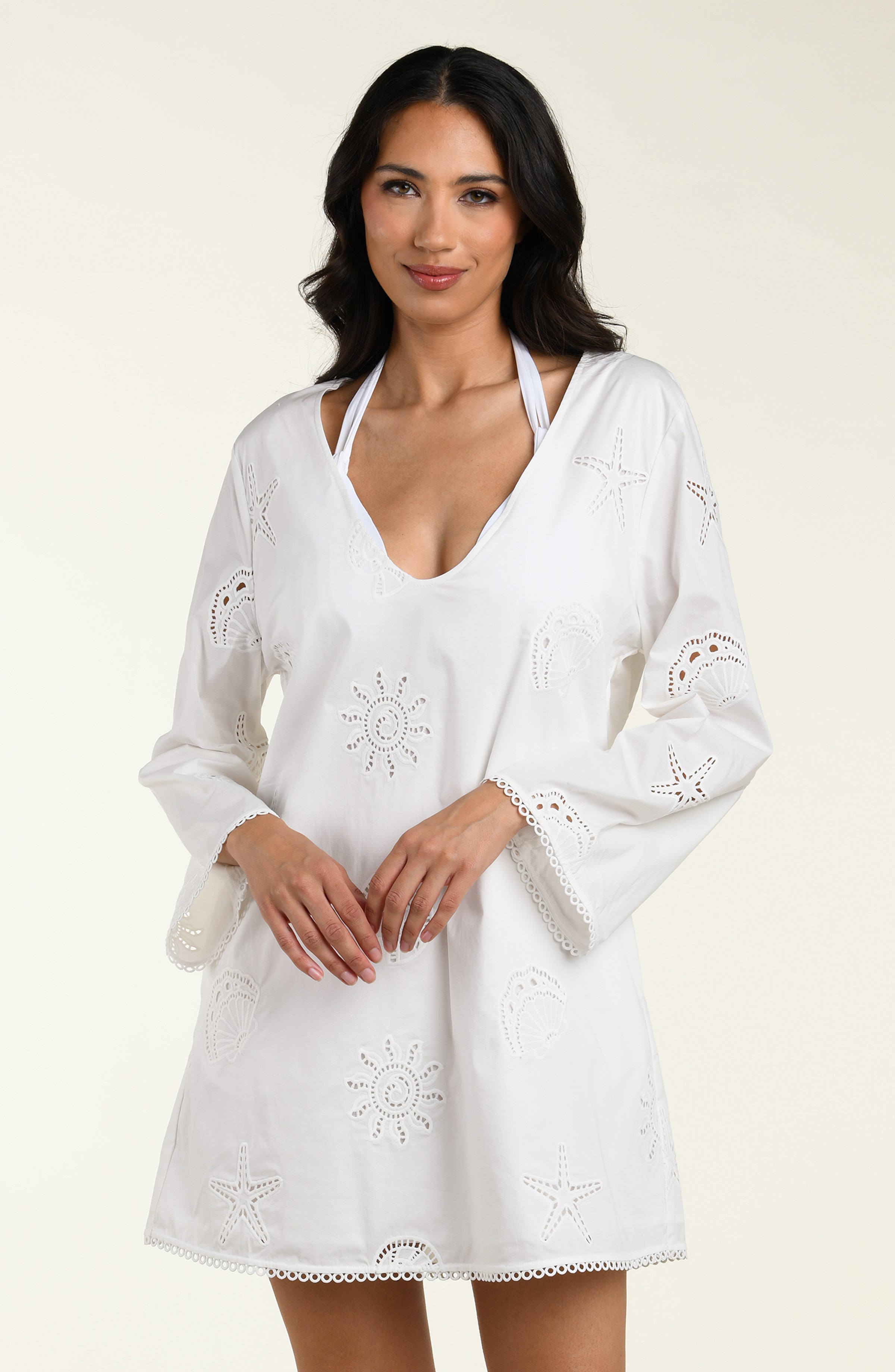 Woman wearing a white long sleeve tunic against a white background. 