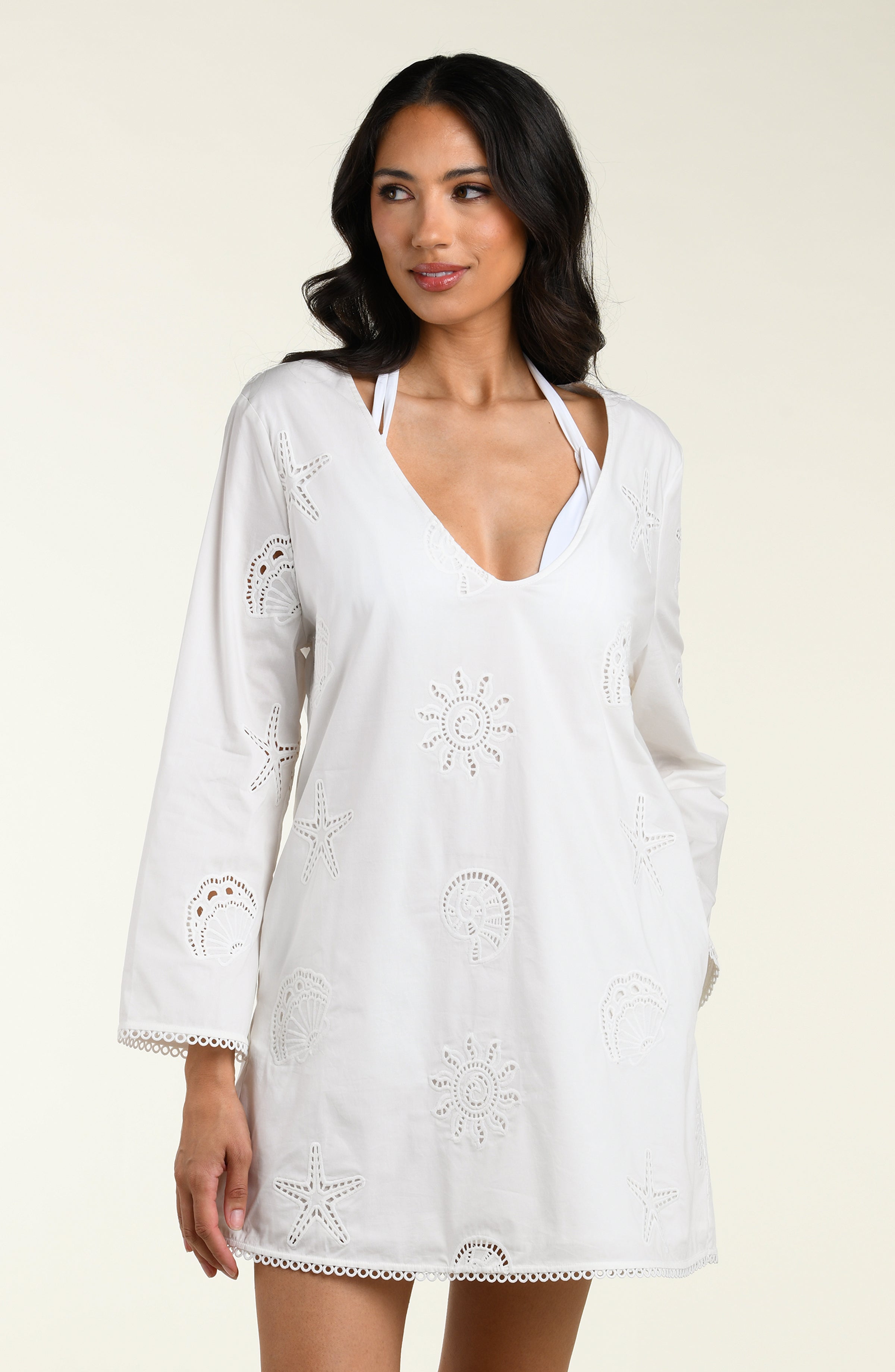 Woman wearing a white long sleeve tunic against a white background. 