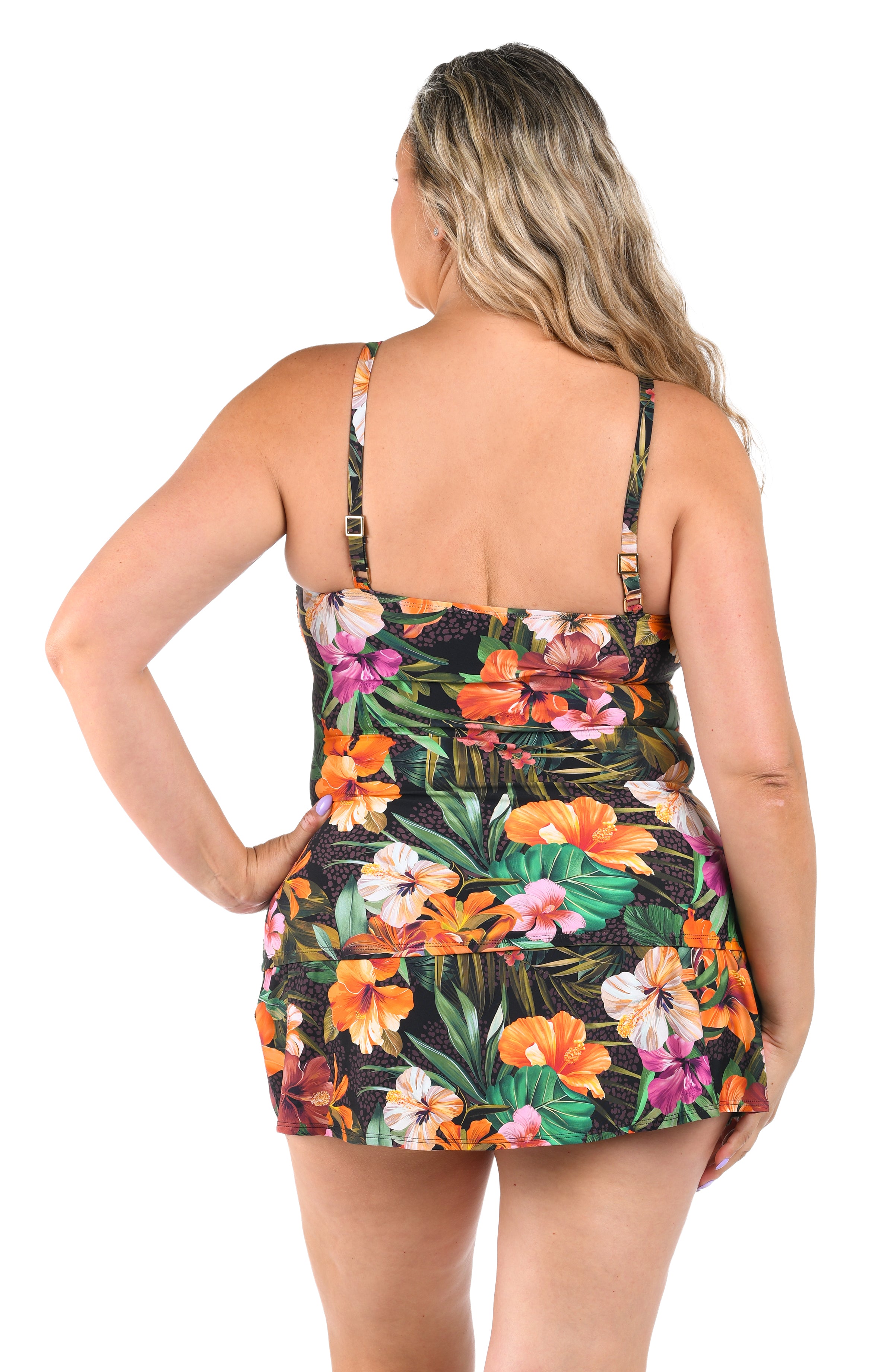 Woman wearing a tropical colored tankini top and matching swim skirt against a white background. 