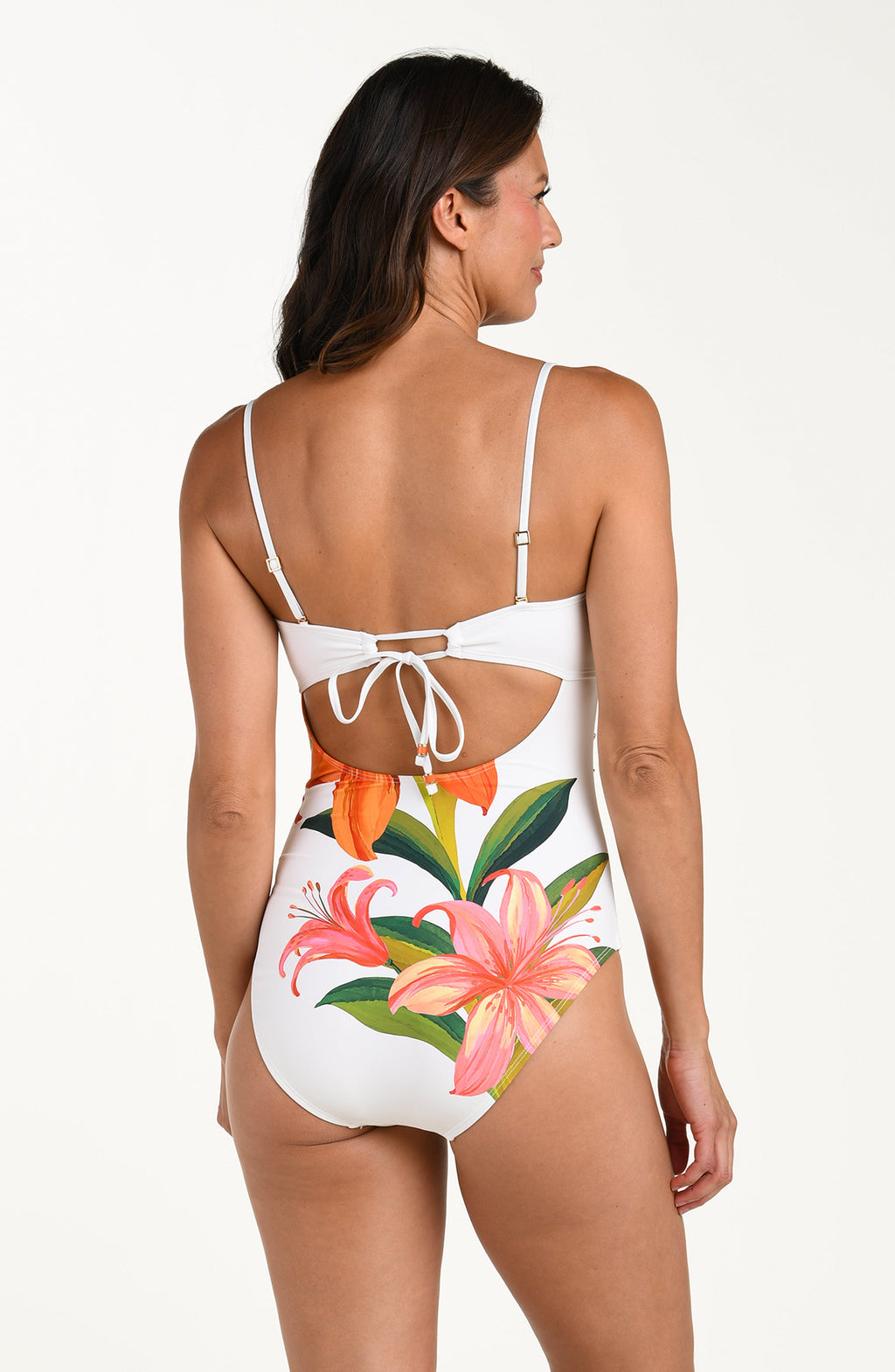 Woman wearing a tropical colored one piece swimsuit with floral design on a white background