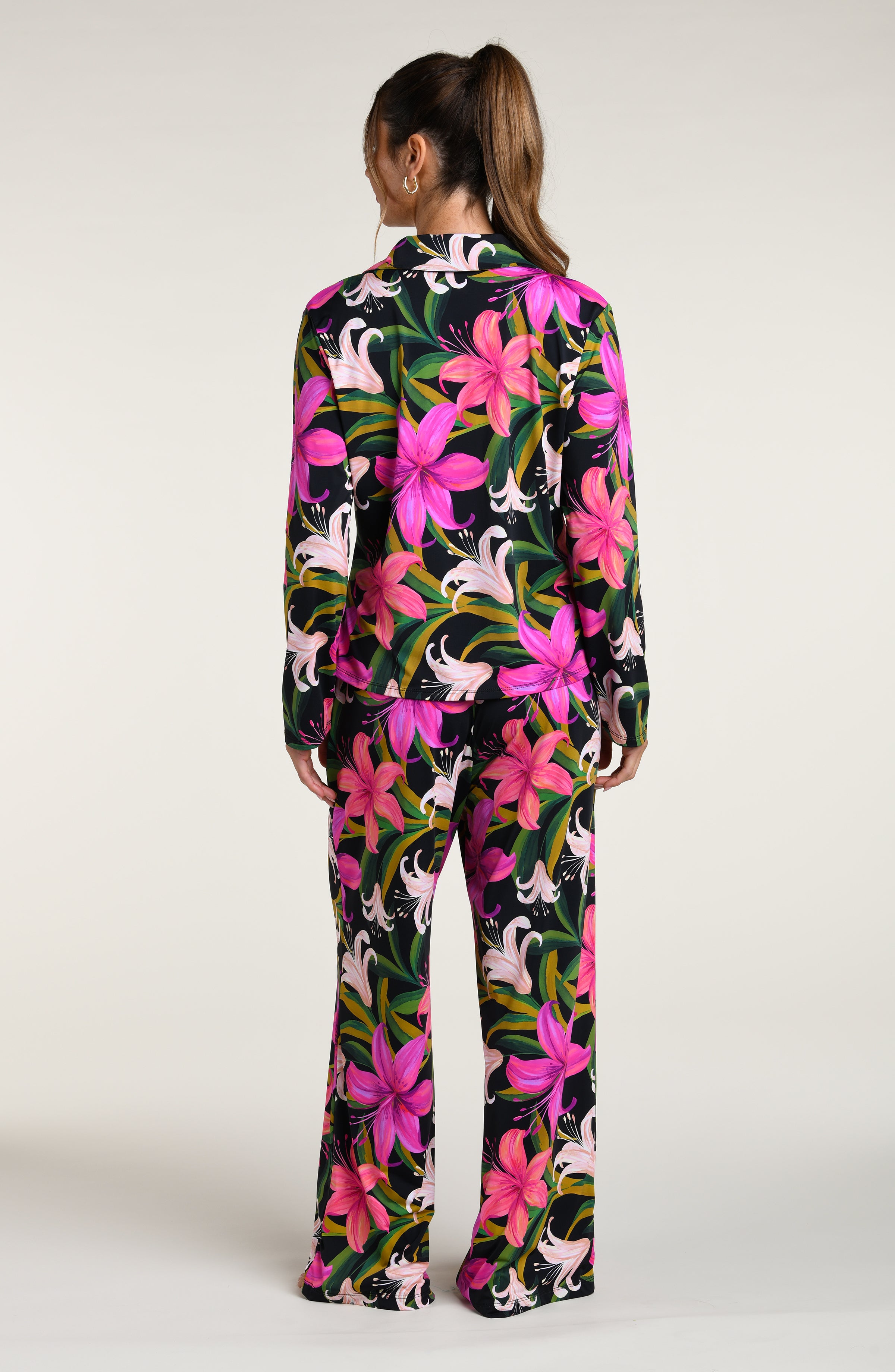 Woman wearing a colorful tropical long sleeve and pant pajama set against a white background.
