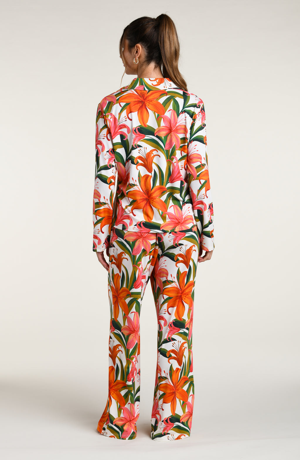 Woman wearing a colorful tropical long sleeve and pant pajama set against a white background.
