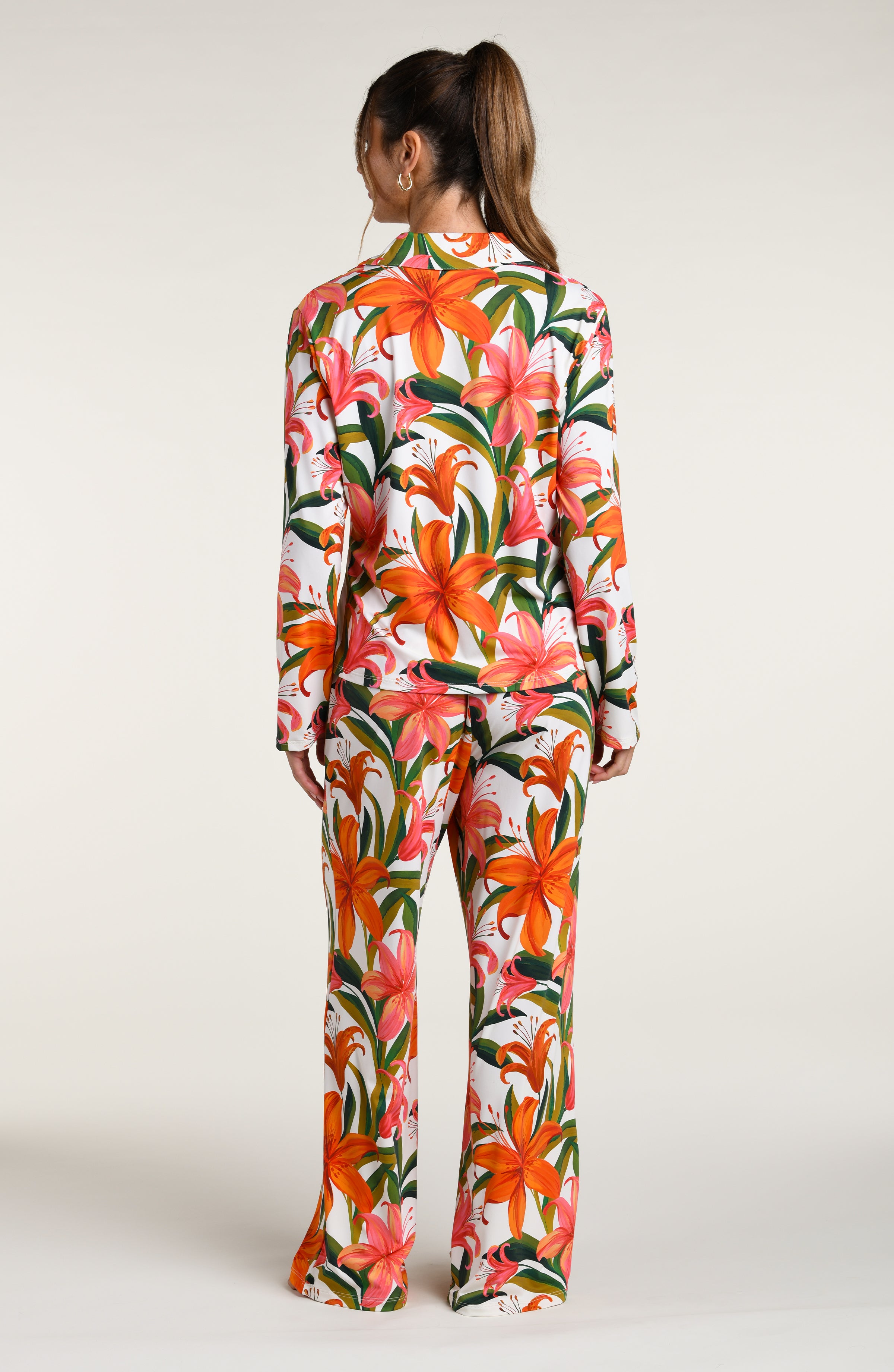 Woman wearing a colorful tropical long sleeve and pant pajama set against a white background.