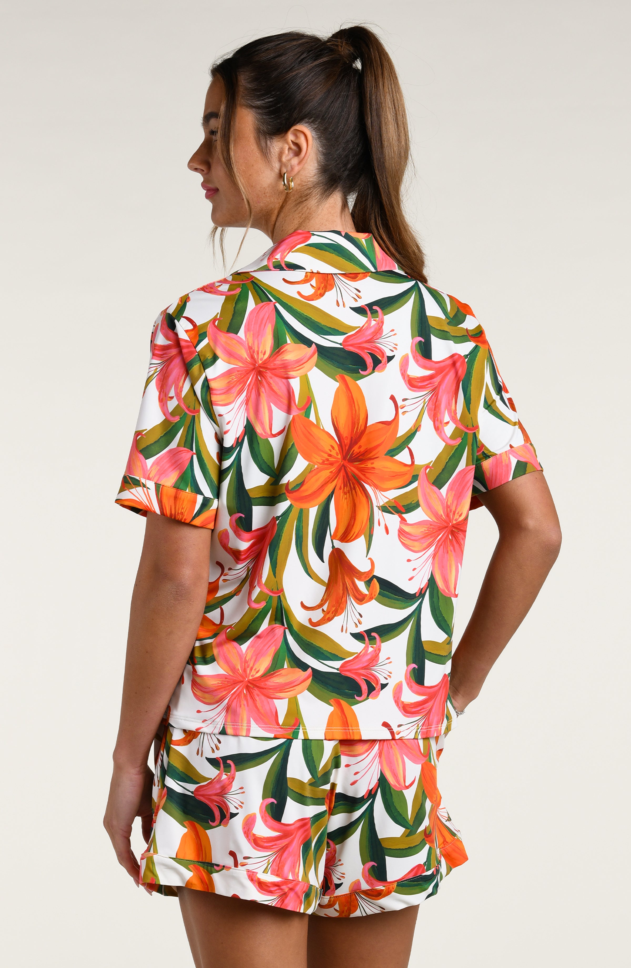 Woman wearing a colorful tropical long sleeve and short pajama set against a white background.